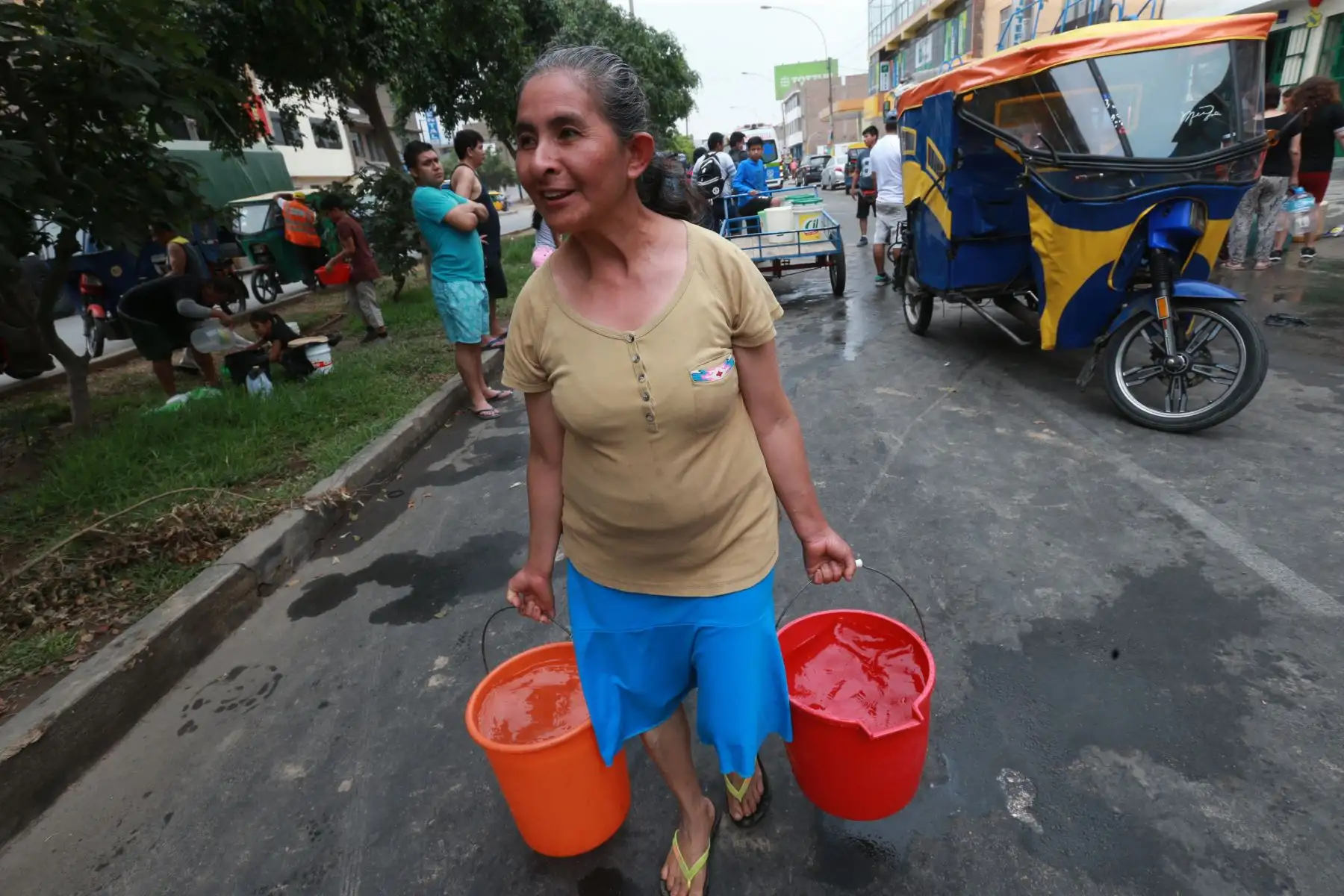 Vecina de la zona afectada de San Juan de Lurigancho, carga baldes de agua repartidos por Cisterna que llego para brindar ayuda. Foto: ANDINA/Norman Córdova