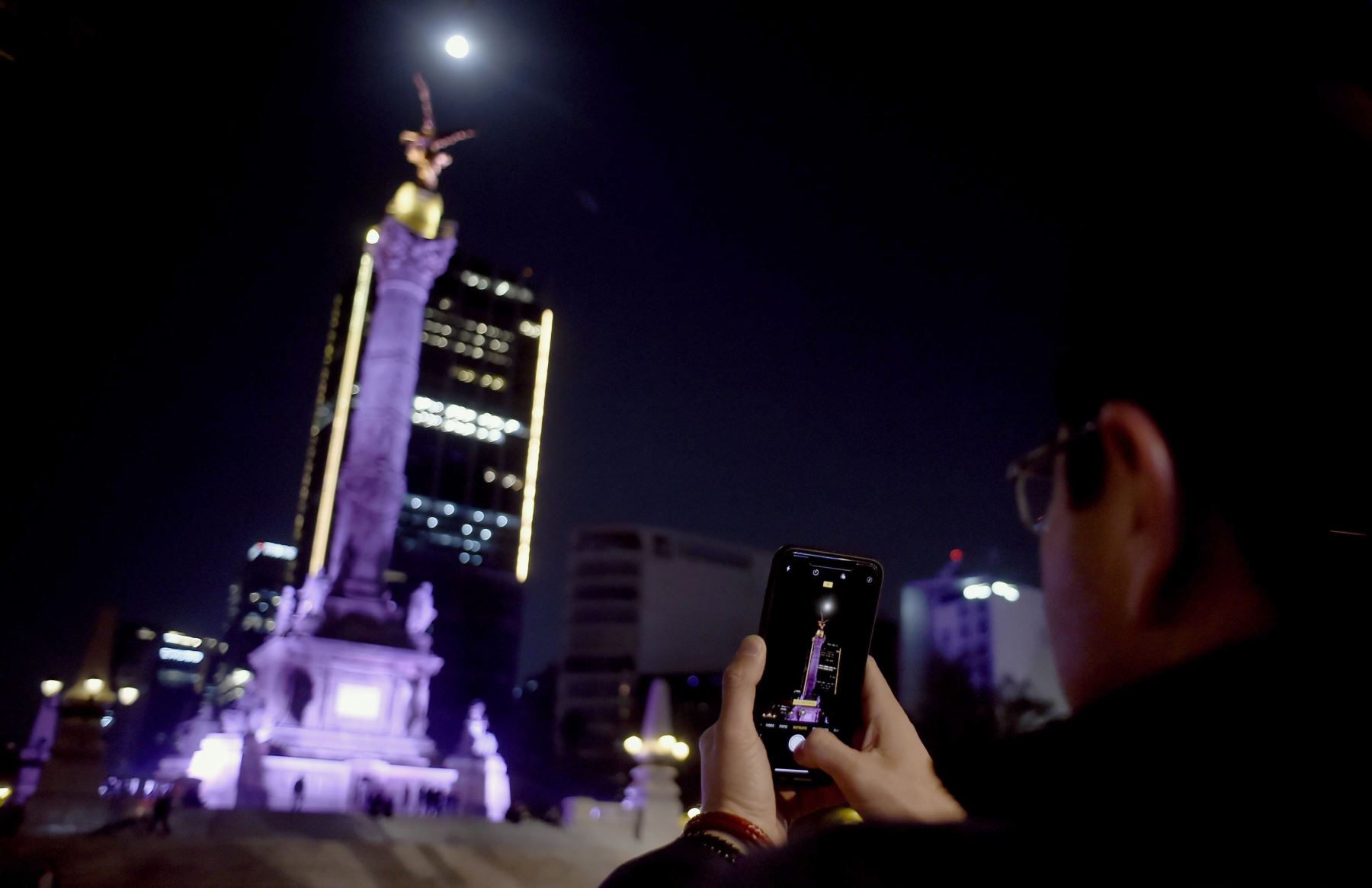 Un hombre está tomando fotos de la Súper Luna durante el inicio del eclipse lunar total, en el Ángel de la Independencia en la Ciudad de México el 20 de enero de 2019. Foto:AFP