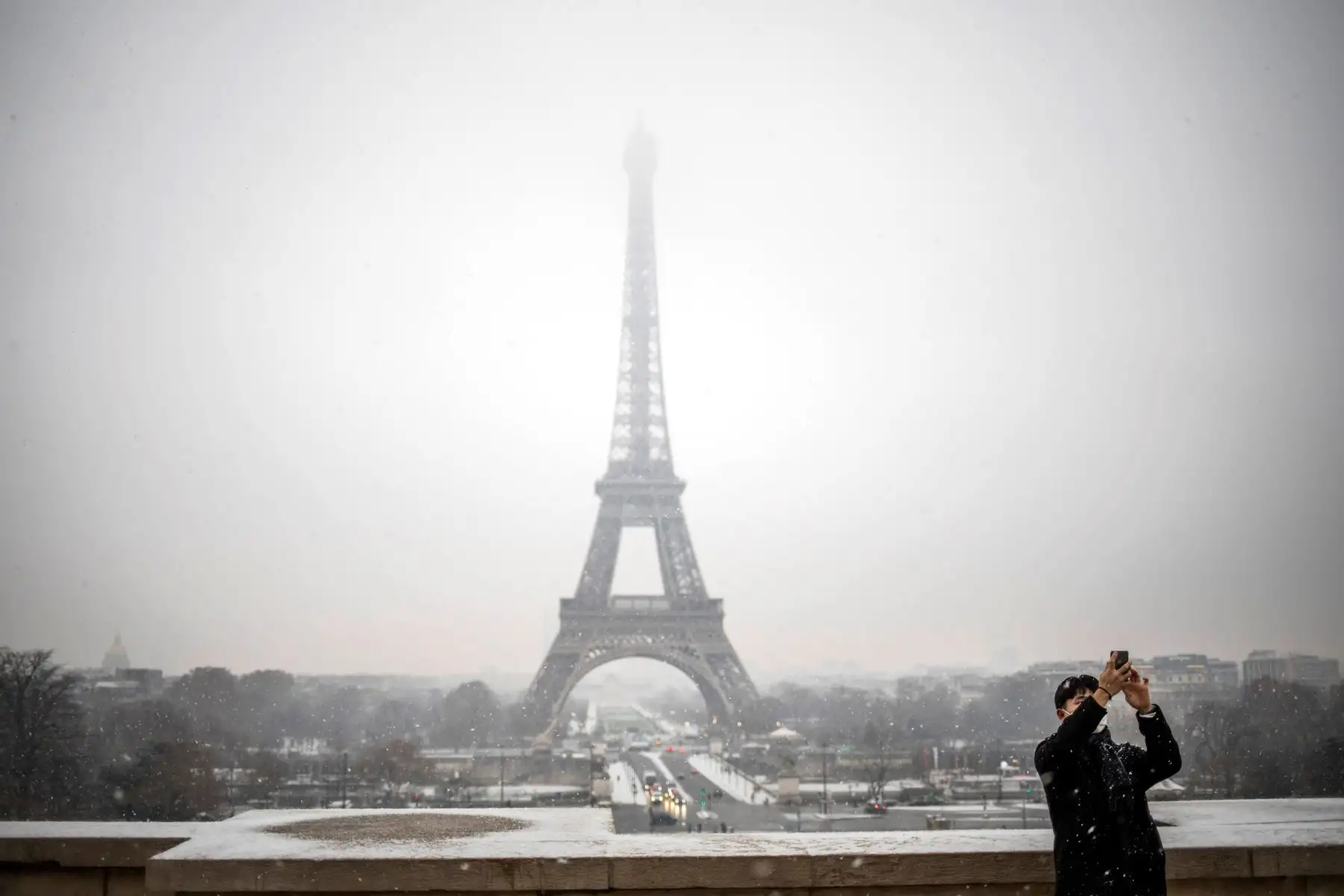 Un turista se toma una foto delante de la Torre Eiffel durante una nevada este martes en París (Francia). Las nevadas afectan el norte del país. EFE