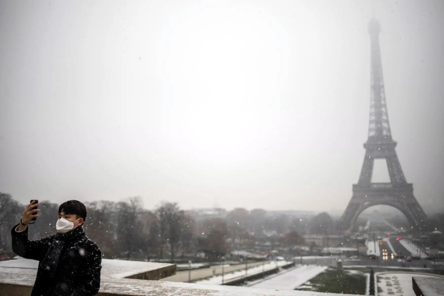 Un hombre se toma una foto delante de la Torre Eiffel durante una nevada este martes en París (Francia). Las nevadas afectan el norte del país. EFE
