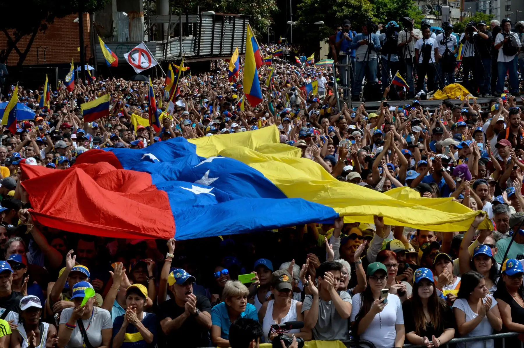La gente escucha al jefe de la Asamblea Nacional de Venezuela, Juan Guaido (fuera de trama), durante un mitin de oposición en masa contra el líder Nicolás Maduro en el que se declaró a sí mismo "presidente interino" del país, en el aniversario de un levantamiento de 1958 que derrocó a una dictadura militar en Caracas el 23 de enero de 2019. "Juro asumir formalmente los poderes ejecutivos nacionales como presidente interino de Venezuela.AFP