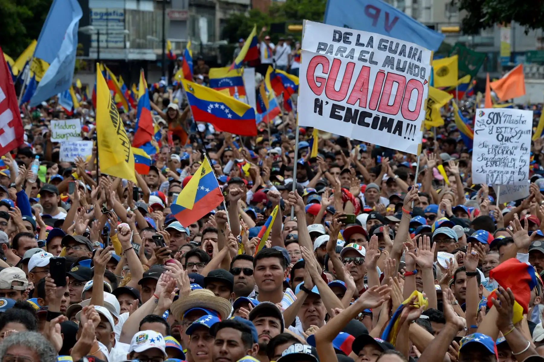 La gente aplaude mientras escucha al jefe de la Asamblea Nacional de Venezuela, Juan Guaido (fuera de trama), durante un mitin de oposición en masa contra el líder Nicolás Maduro, en el que se declaró a sí mismo "presidente interino", en el aniversario de un levantamiento de 1958 que derrocó a una dictadura militar. , en Caracas, el 23 de enero de 2019. "Juro asumir formalmente los poderes ejecutivos nacionales como presidente interino de Venezuela.AFP