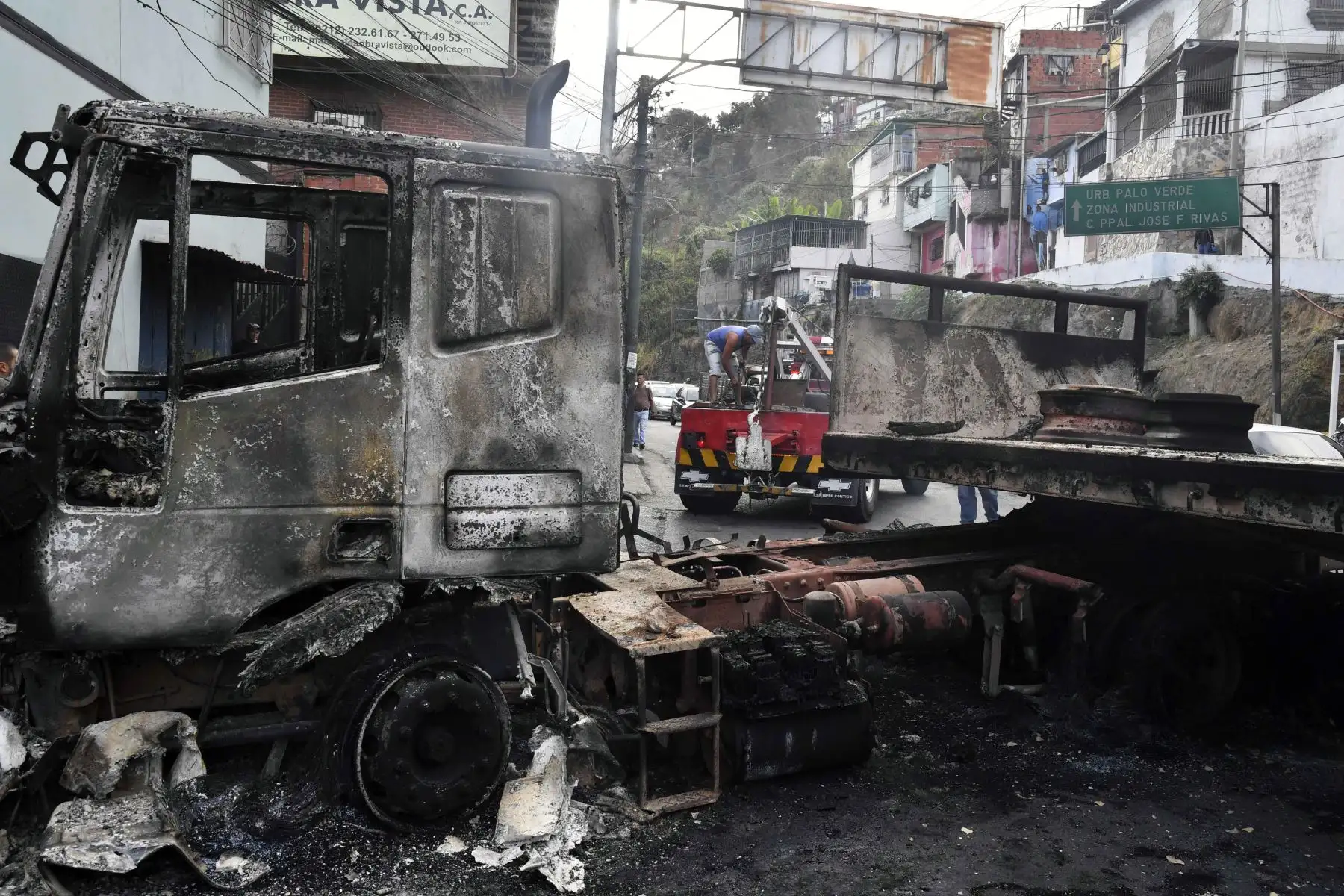 Los trabajadores usan una grúa para mover los restos de un camión que se quemó durante las protestas de la noche anterior en el emblemático vecindario de Petare en Caracas, el 24 de enero de 2019. El jefe de la ONU, Antonio Guterres, pidió el jueves un diálogo para detener la crisis política de Venezuela. Saliéndose de control, el líder opositor Juan Guaido se declaró a sí mismo presidente interino.  AFP