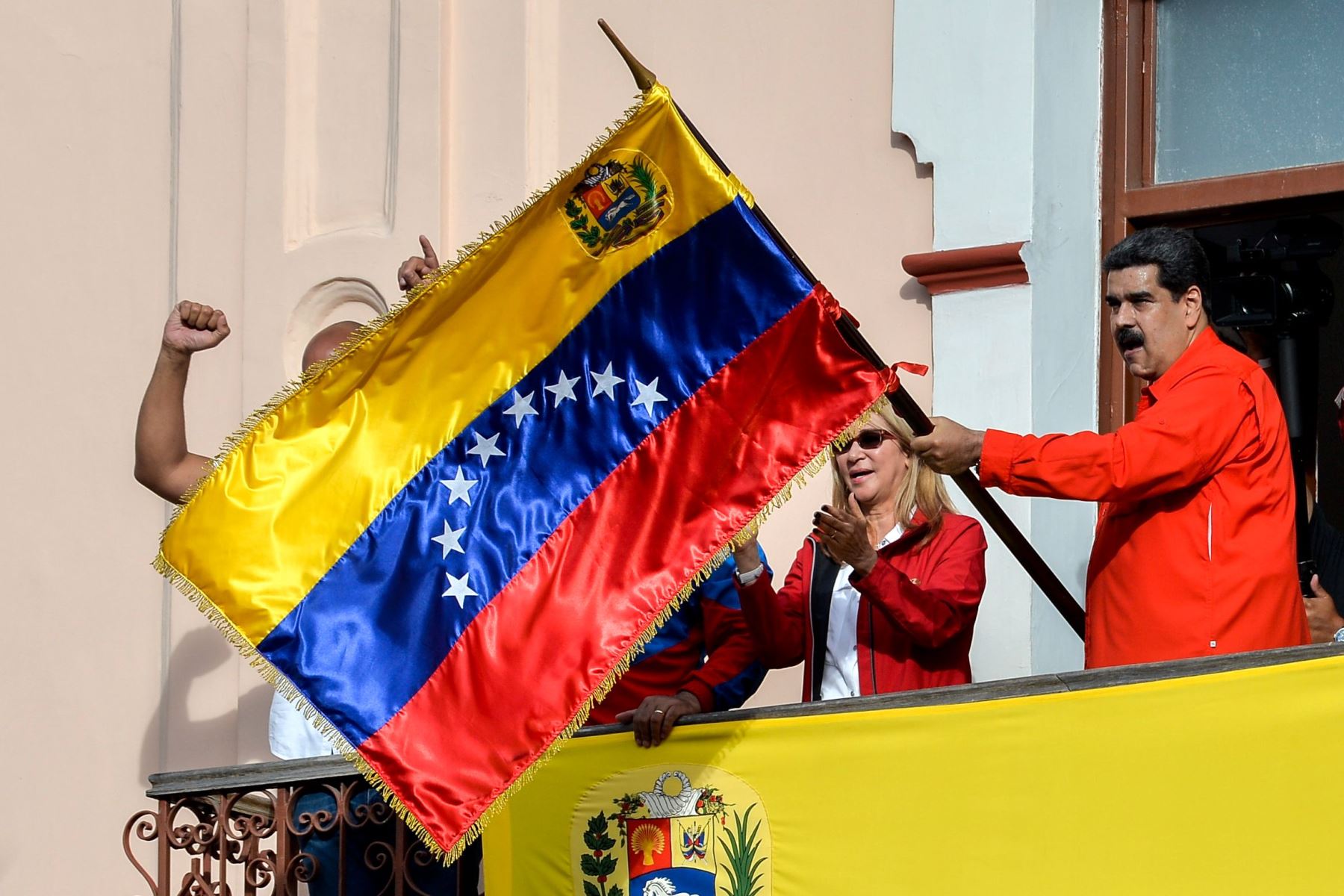 El presidente de Venezuela, Nicolás Maduro, flanqueado por su esposa Cilia Flores, sostiene una bandera venezolana mientras habla desde un balcón en el Palacio Presidencial de Miraflores Foto: AFP