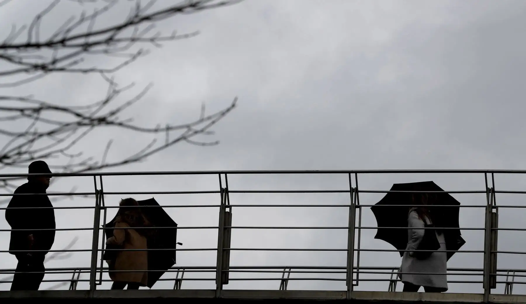 Varias personas se protegen del agua y del viento en la capital vizcaína, Bilbao, donde los cielos en Euskadi se presentaron cubiertos con lluvias, persistentes. EFE/Luis Tejido.
