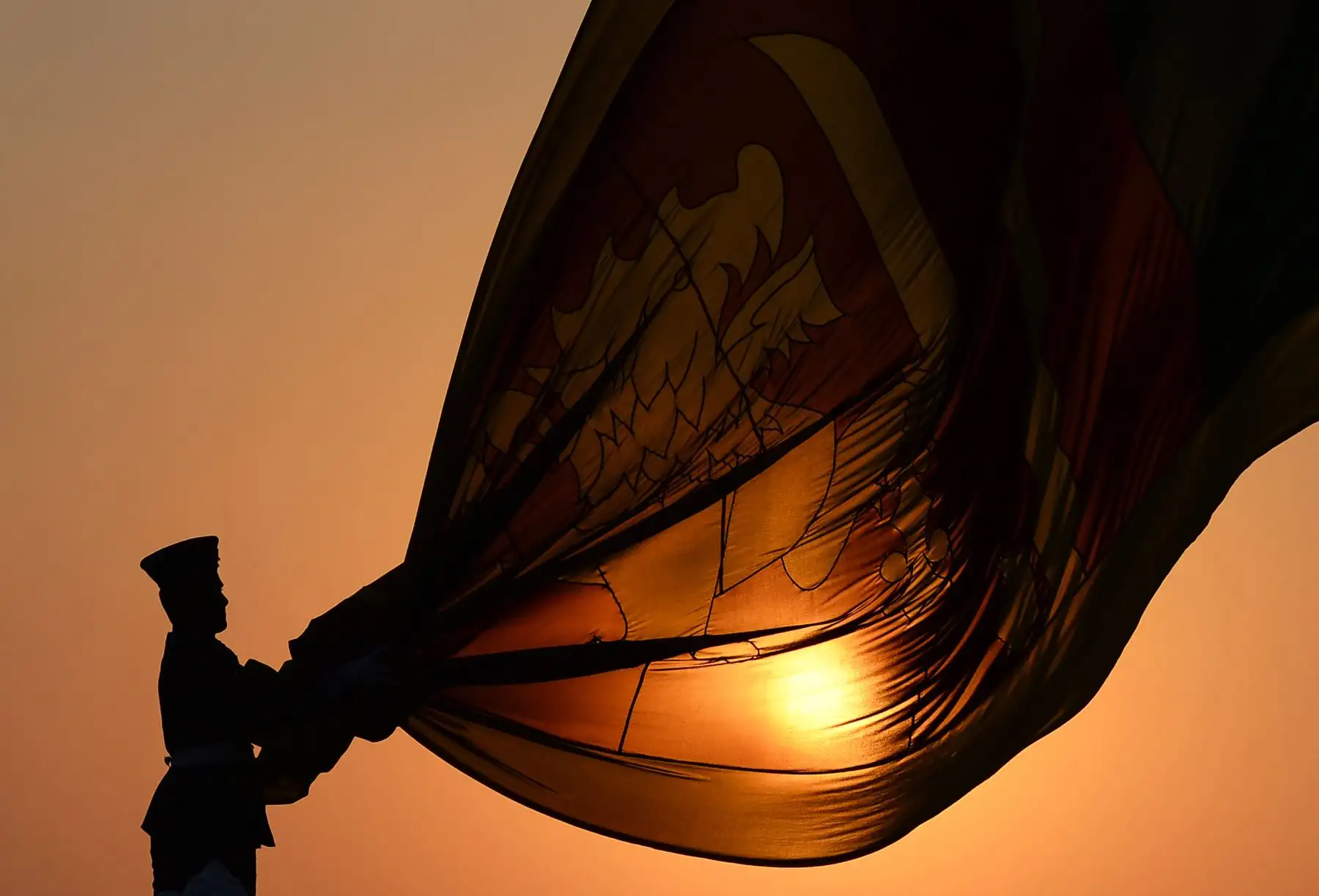 Los oficiales de la Fuerza Aérea de Sri Lanka sostienen la bandera nacional mientras se baja como parte de una ceremonia diaria durante la puesta de sol en el paseo de Galle Face Green en Colombo. Foto: AFP