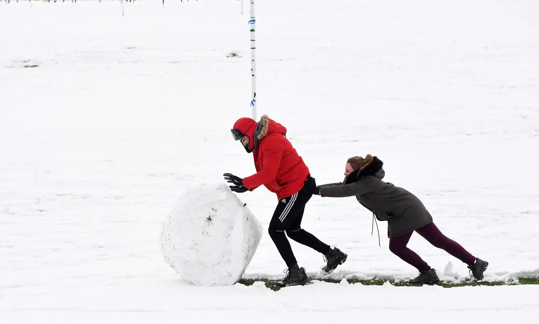 Una pareja empuja una gran bola de nieve  en Wycombe (Reino Unido), donde, al igual que en muchas otras partes del paÌs, las bajas temperaturas y las fuertes nevadas han causado imprevistos a la hora de viajar al exterior o desplazarse por el país. EFE