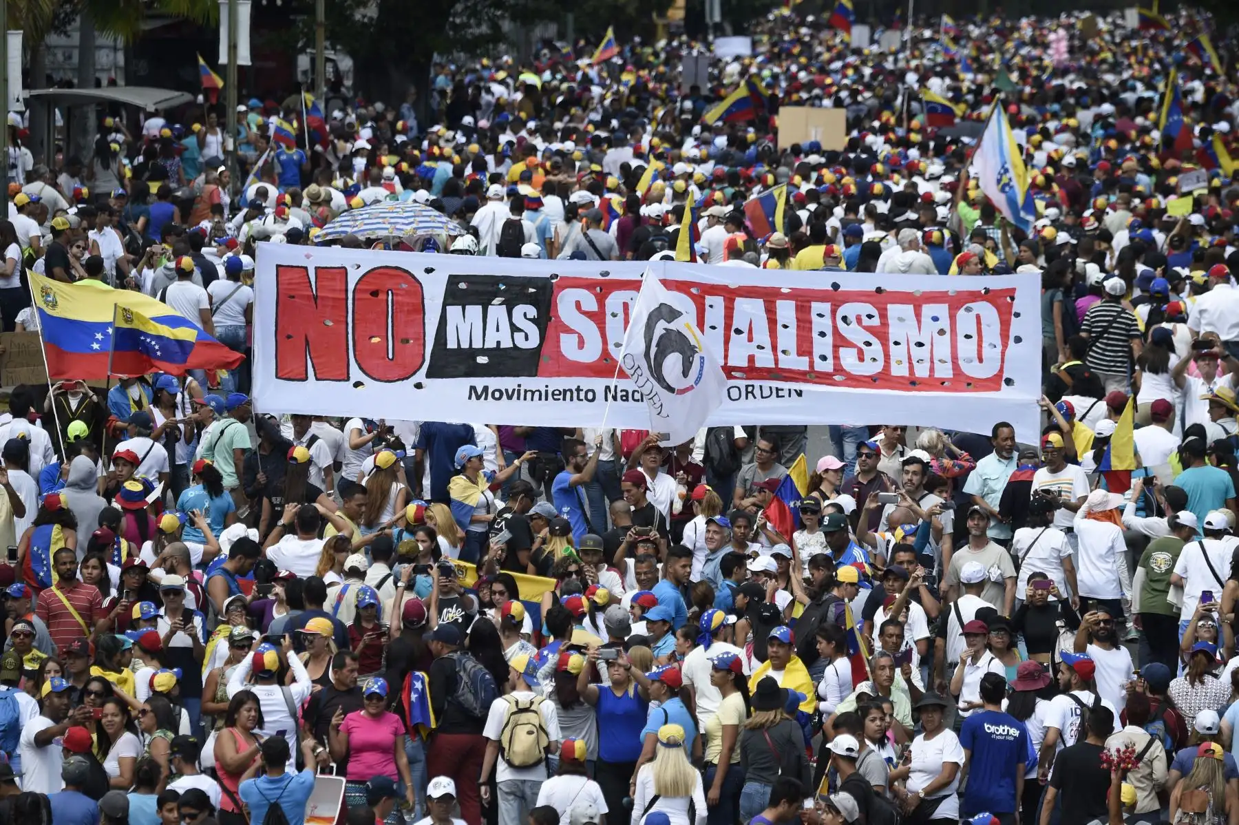 Los partidarios de la oposición sostienen una pancarta que dice "No más socialismo" durante una reunión con el líder opositor venezolano Juan Guaido, en Caracas. Foto: AFP/Juan Barreto