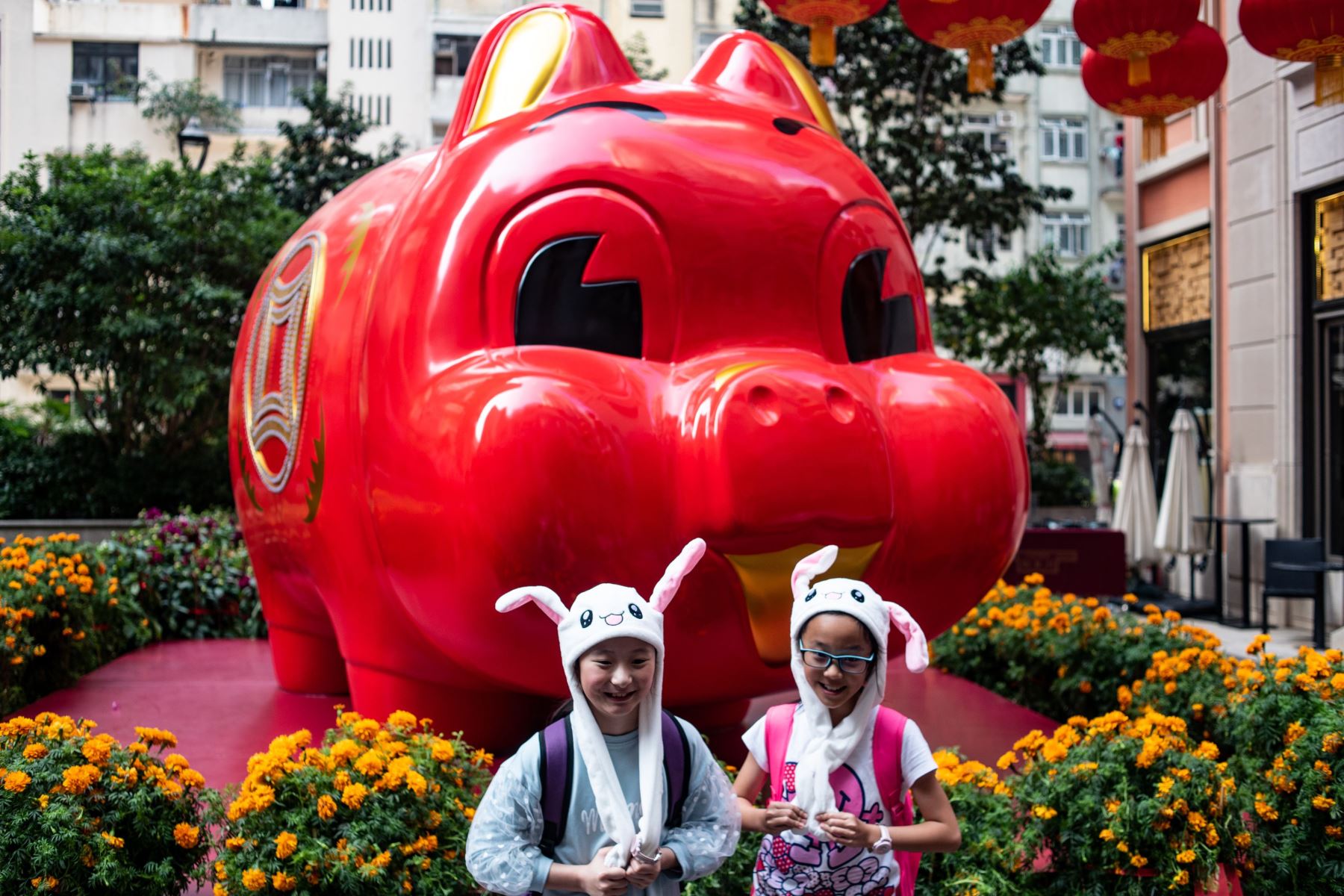 Niños con sombreros de animales posan frente a una instalación de cerdos gigantes para el Año Nuevo Lunar en Hong Kong Foto: AFP