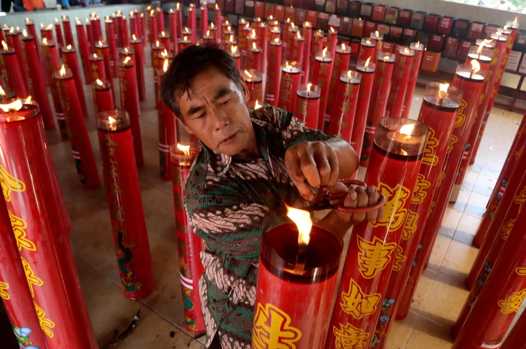 Un hombre enciende una vela durante los rezos, con motivo de las celebraciones del Año Nuevo Lunar en el templo Gayatri en Cilodong (Indonesia). Chinos a lo largo del país y en las comunidades del extranjero dieron hoy la bienvenida al Año Nuevo lunar, en el que el despreocupado y generoso cerdo, sustituye al alegre pero inconformista perro. Foto: EFE