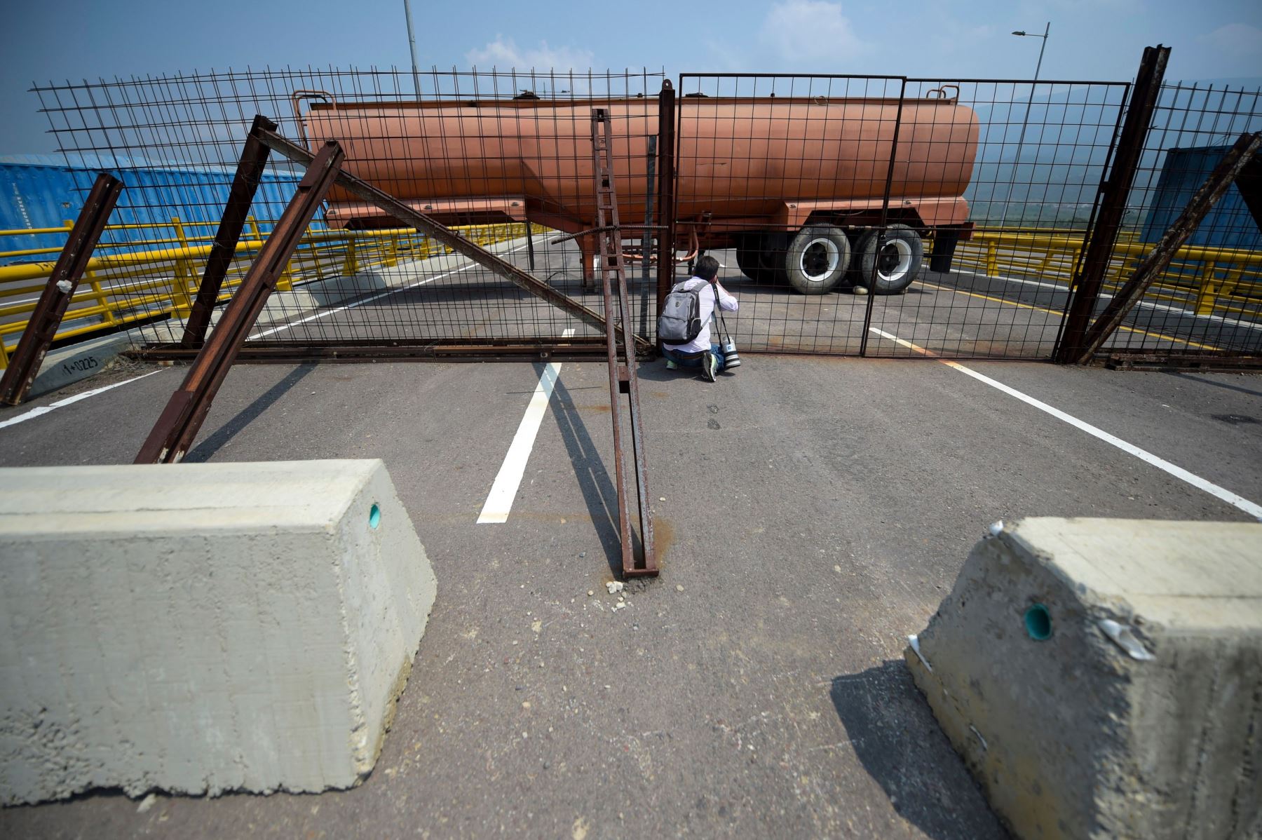 Un fotógrafo acciona su cámara mientras las fuerzas militares venezolanas bloquean con contenedores el puente Tienditas, que une Táchira (Venezuela) y Cúcuta (Colombia), el 6 de febrero del 2019.  Foto: AFP.
