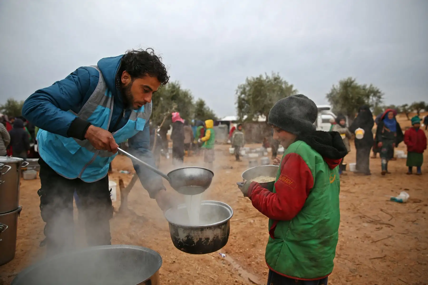 Un niño sirio recibe alimentos distribuidos por un trabajador humanitario en un campamento provisional para personas desplazadas, cerca de la aldea de Yazi Bagh, a unos seis kilómetros del cruce fronterizo de Bab al-Salamah entre Siria y Turquía en el norte de la provincia de Aleppo. AFP