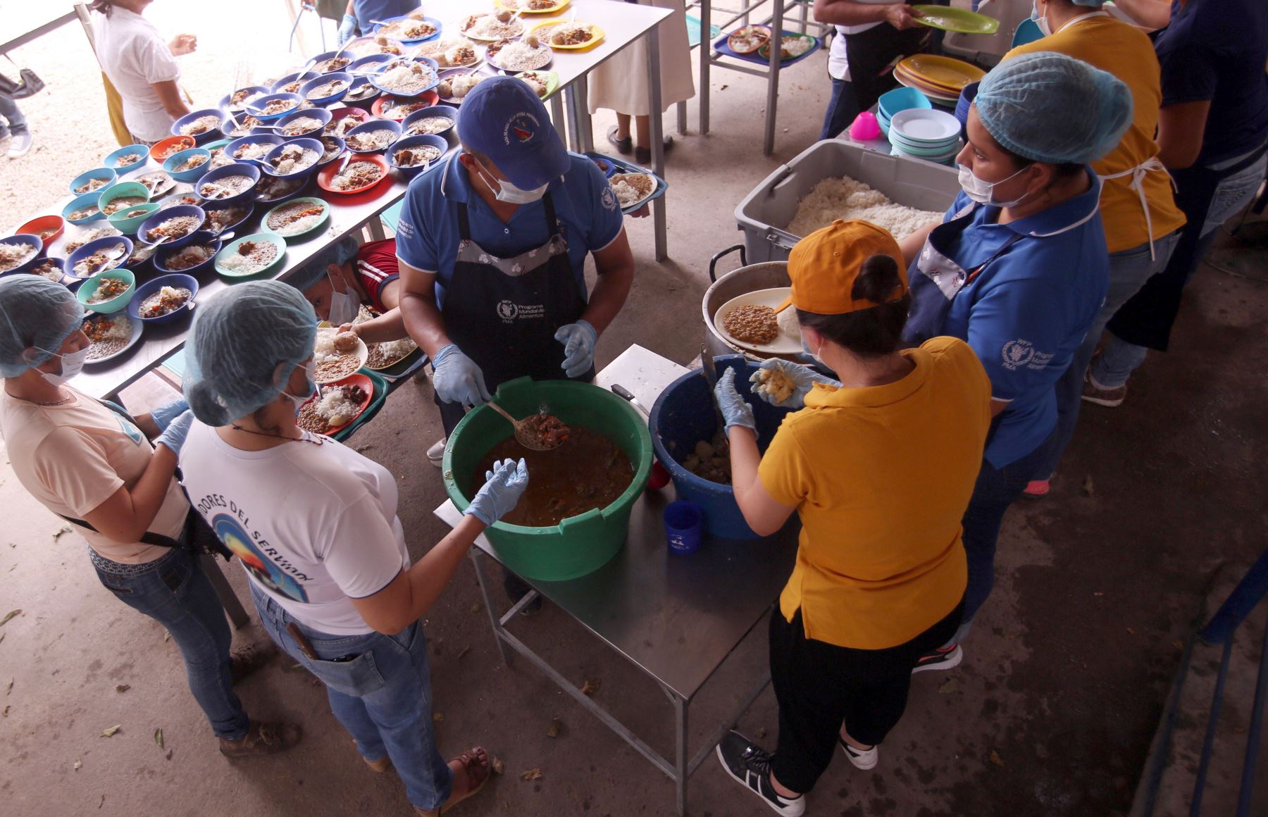 Un grupo de trabajadores sirve una ración de comida a ciudadanos venezolanos que cruzan la frontera Venezuela - Colombia para recibir la ayuda.