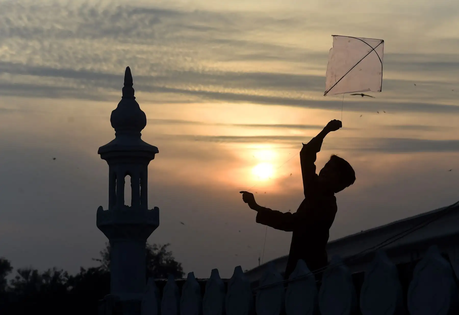 Un niño pakistaní vuela una cometa en el techo de una mezquita durante la puesta de sol en Lahore el 11 de febrero de 2019. Foto: AFP/ARIF ALI