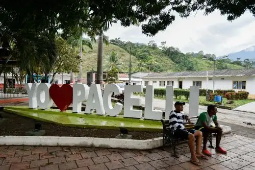 Hombres descansan en un banco en una plaza en Pacelli, una ciudad en la región del Catatumbo donde muchos migrantes venezolanos trabajan como "raspachines" (recolector de hojas de coca). Foto: AFP.