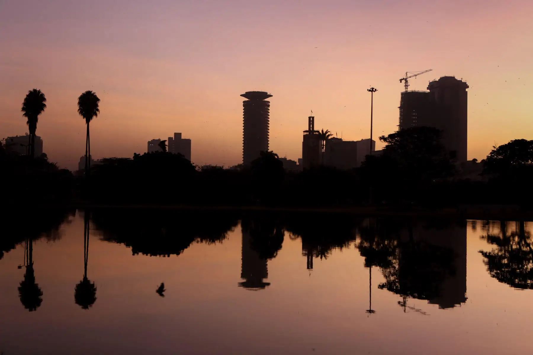 Silueta de varios edificios a orillas de un lago del parque Uhuru a la salida del sol este martes en Nairobi (Kenia). EFE