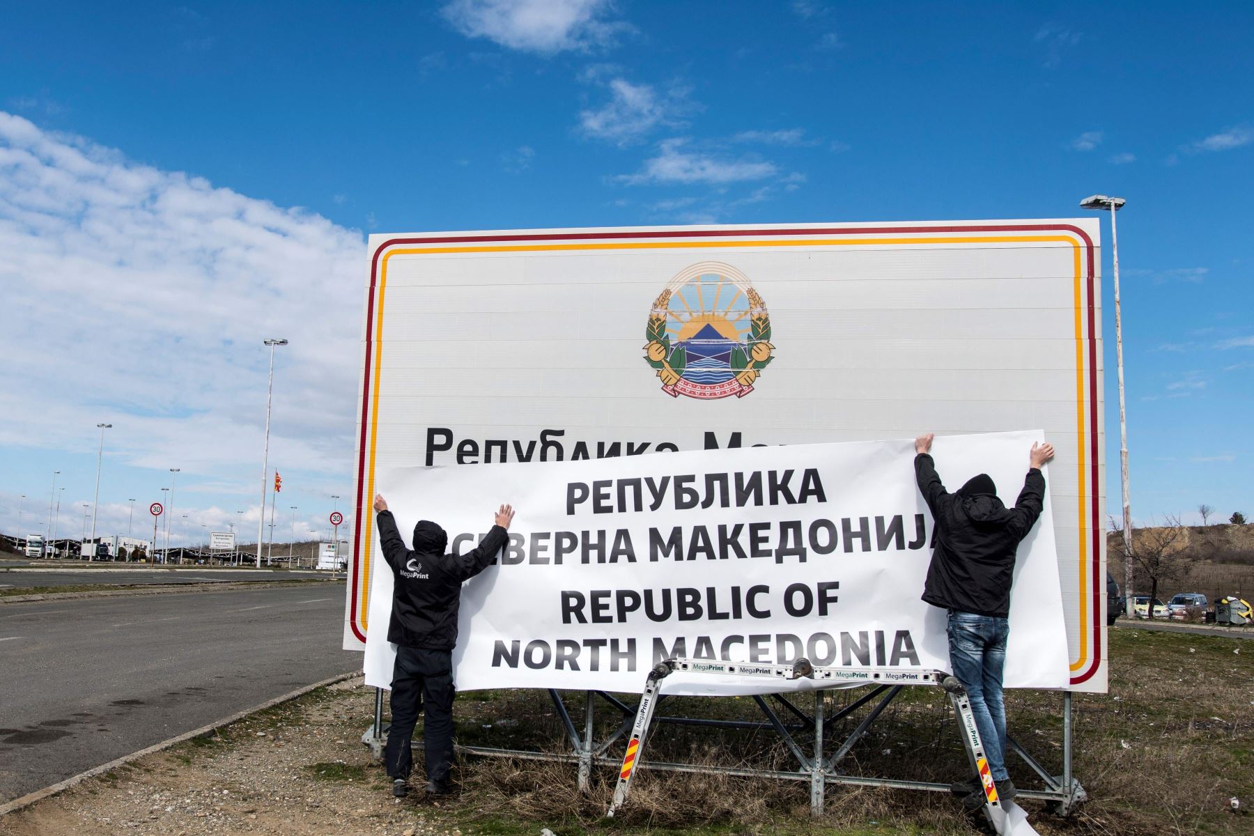 Trabajadores cambian los letreros en la frontera entre Macedonia y Grecia cerca de Gevgelija el 13 de febrero de 2019. Foto: AFP