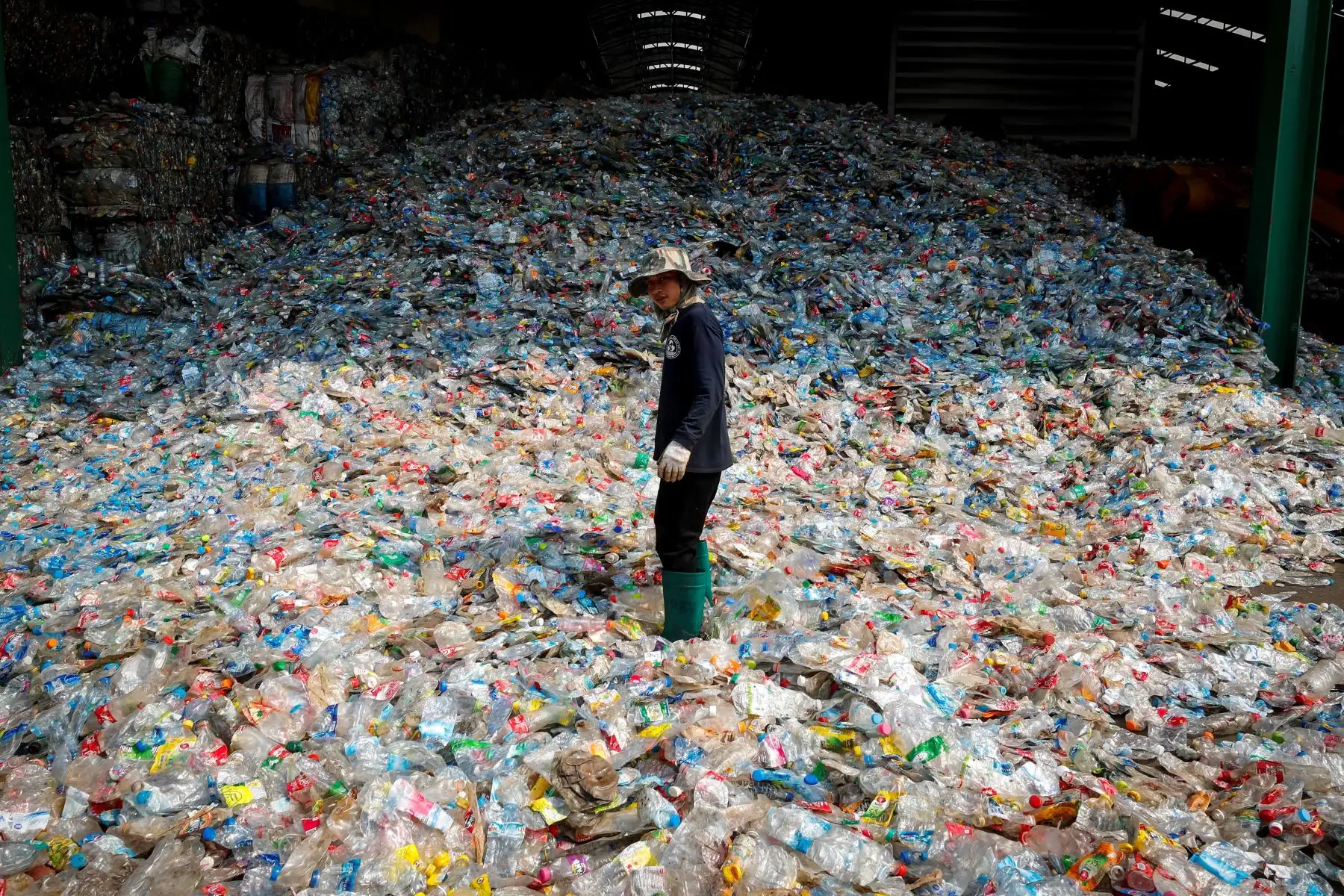 Un trabajador migrante camina entre las botellas de plástico prensadas que se procesarán para su reciclaje en la planta de Thaiplastic Recycle Group e a las afueras de Bangkok. Tailandia. Thaiplastic Recycle Group tiene más de 100 empleados y durante los últimos 11 años se ha centrado en el reciclaje de botellas de plástico, que se utilizan principalmente para agua y refrescos. Thaiplastic recicla y convierte en poliéster 2.000 toneladas de plástico al mes, y vende el 50% localmente y el otro 50% al extranj