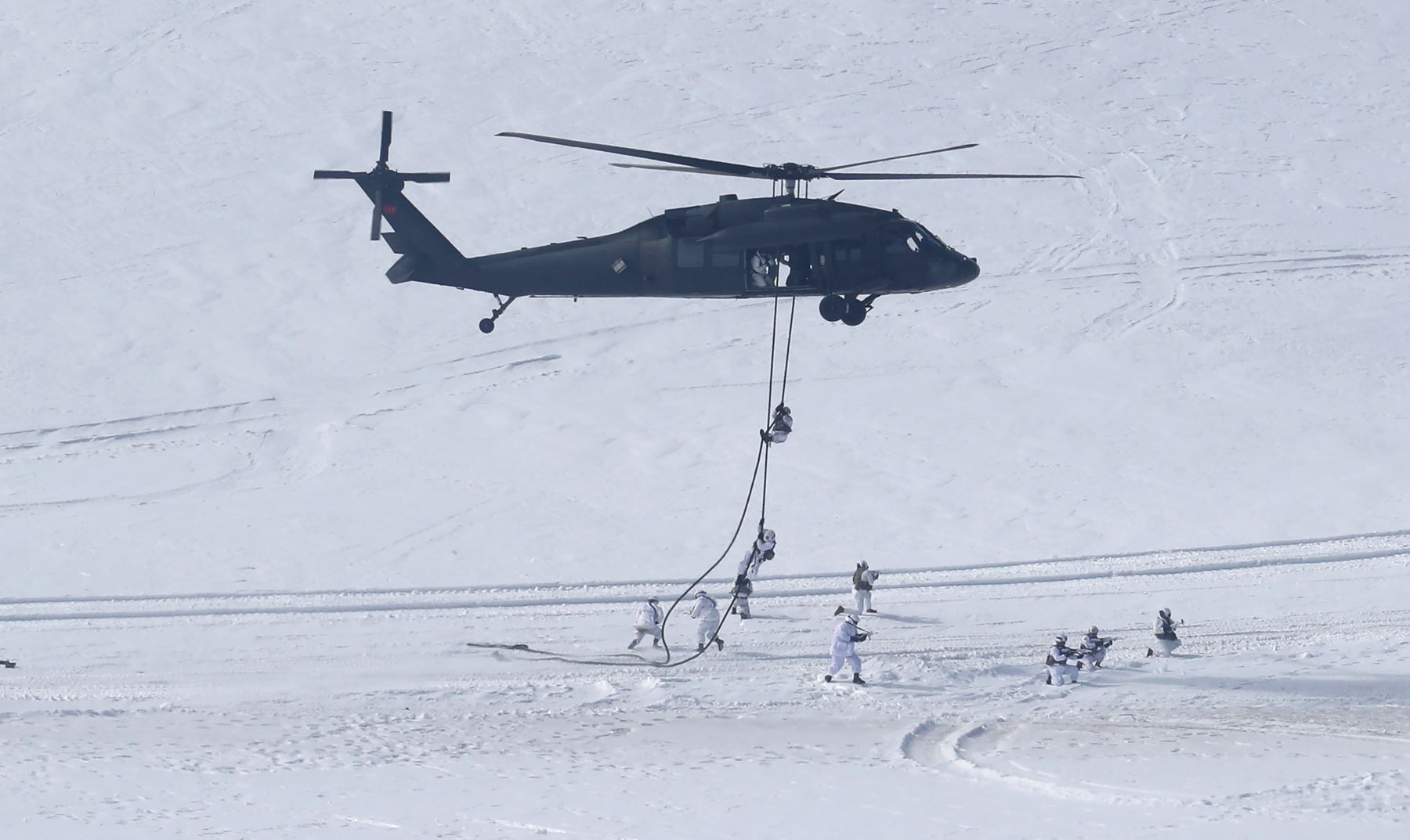 Un helicóptero militar turco se cierne sobre comandos durante el ejercicio combinado de fuego en vivo de invierno de 2019 en una zona montañosa cerca de Kars, al este de Turquía.. AFP