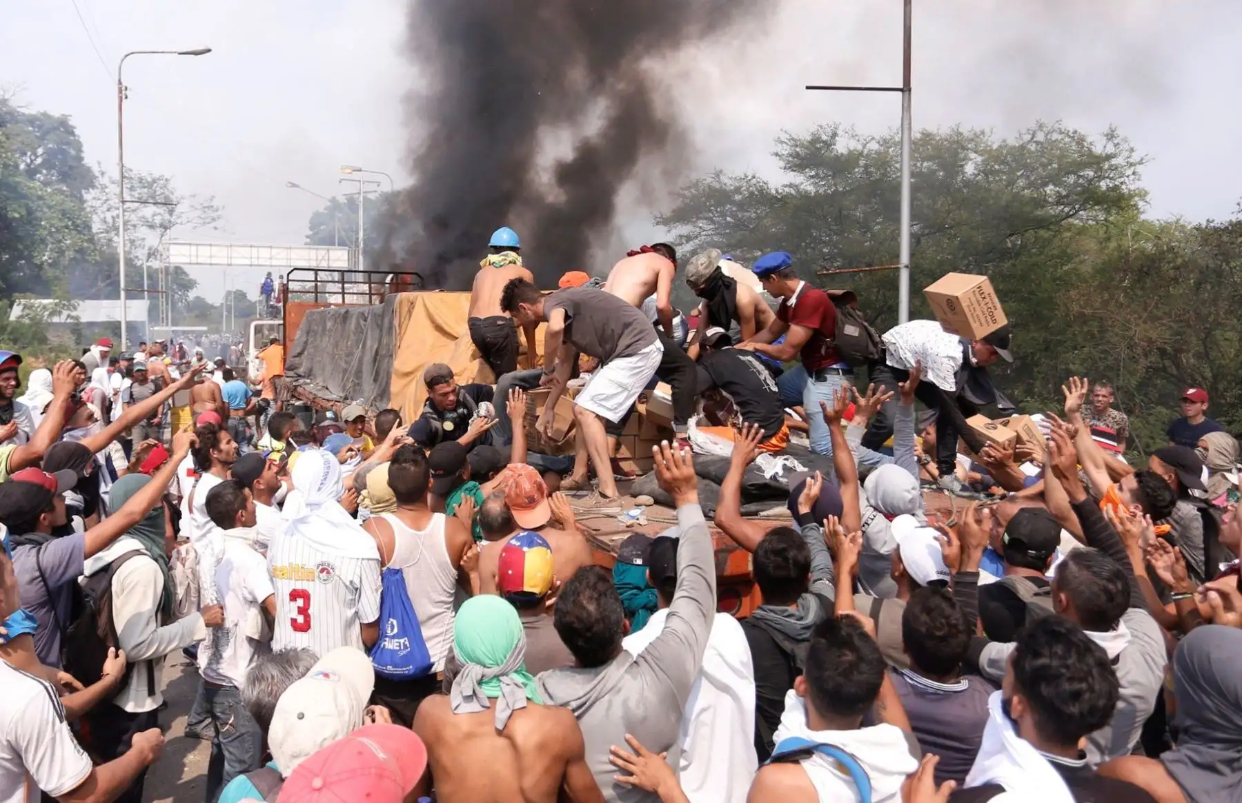 Personas intentan sacar parte de la ayuda humanitaria que se encuentra un camión que fue quemado, por la policia bolivariana en Ureña (Venezuela). EFE