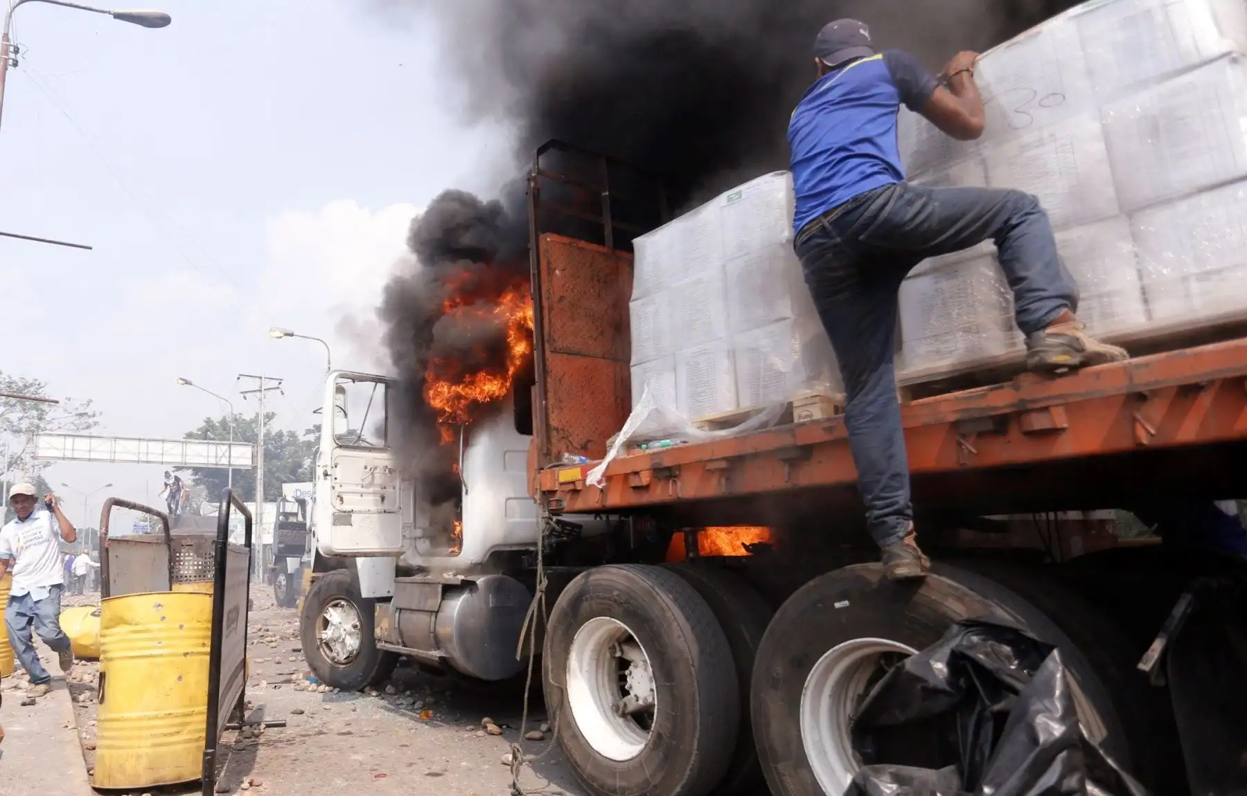 Venezolanos intentan salvar la carga de ayuda humanitaria que esta tarde quemó la policía bolivariana en Ureña, Venezuela. EFE