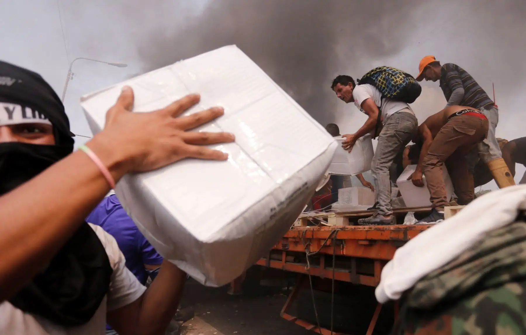 Venezolanos intentan salvar la carga de ayuda humanitaria que esta tarde quemó la policía bolivariana en Ureña, Venezuela. EFE