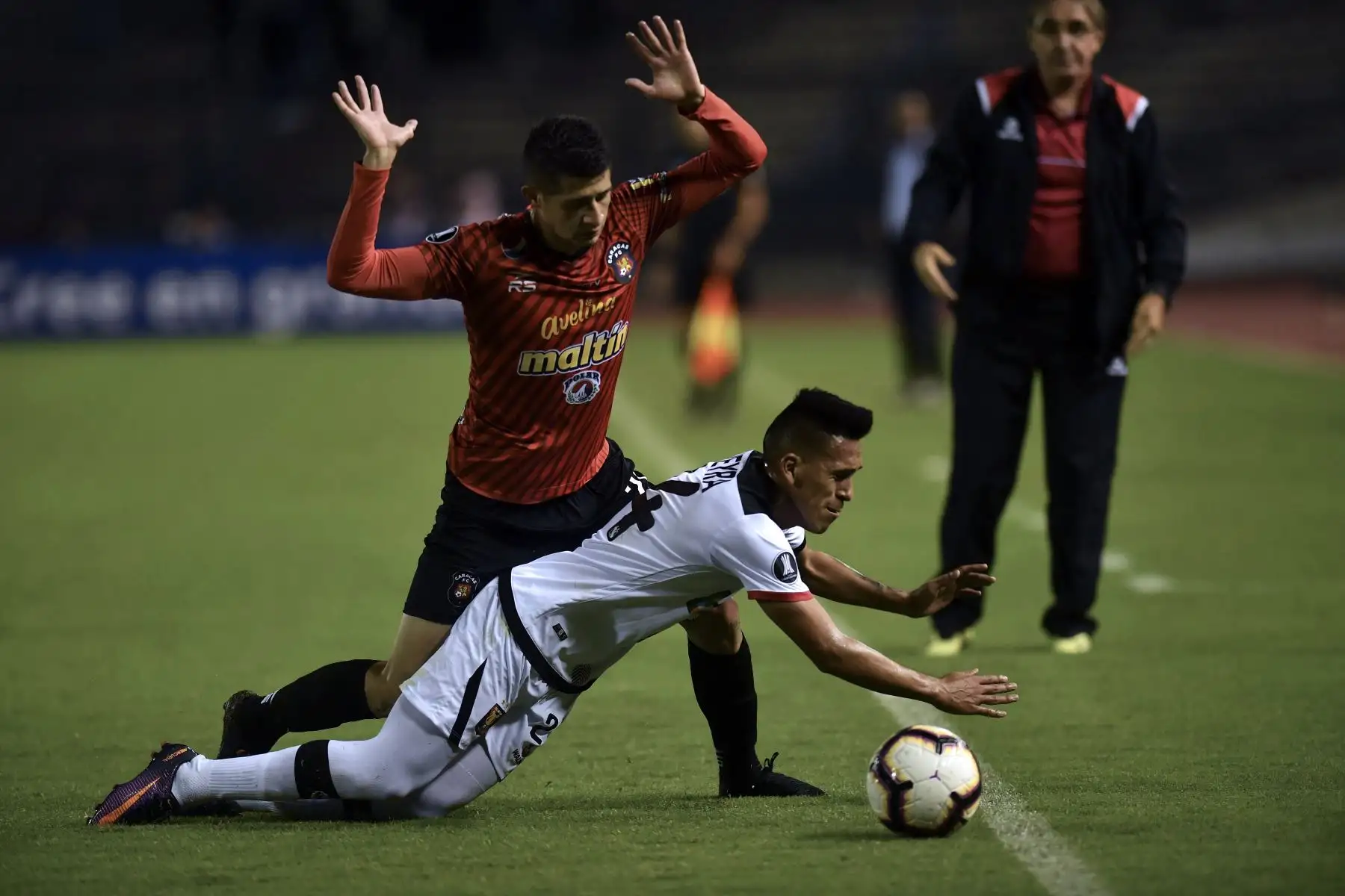 El mediocampista peruano de Melgar, Carlos Neyra (delantero) y el mediocampista de Caracas, Leonardo Flores, compiten por el balón durante su partido de fútbol de la tercera fase de la tercera fase de la Copa Libertadores en el Estadio Olímpico de Caracas. AFP