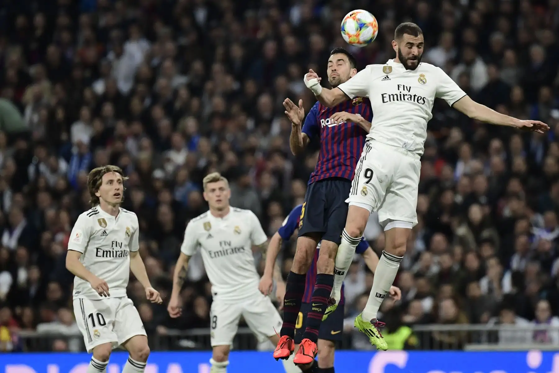 El delantero francés del Real Madrid, Karim Benzema (R) compite con el centrocampista español de Barcelona, Sergio Busquets, durante la semifinal de fútbol de la segunda etapa de la Copa del Rey de España entre el Real Madrid y el Barcelona en el estadio Santiago Bernabeu de Madrid. AFP