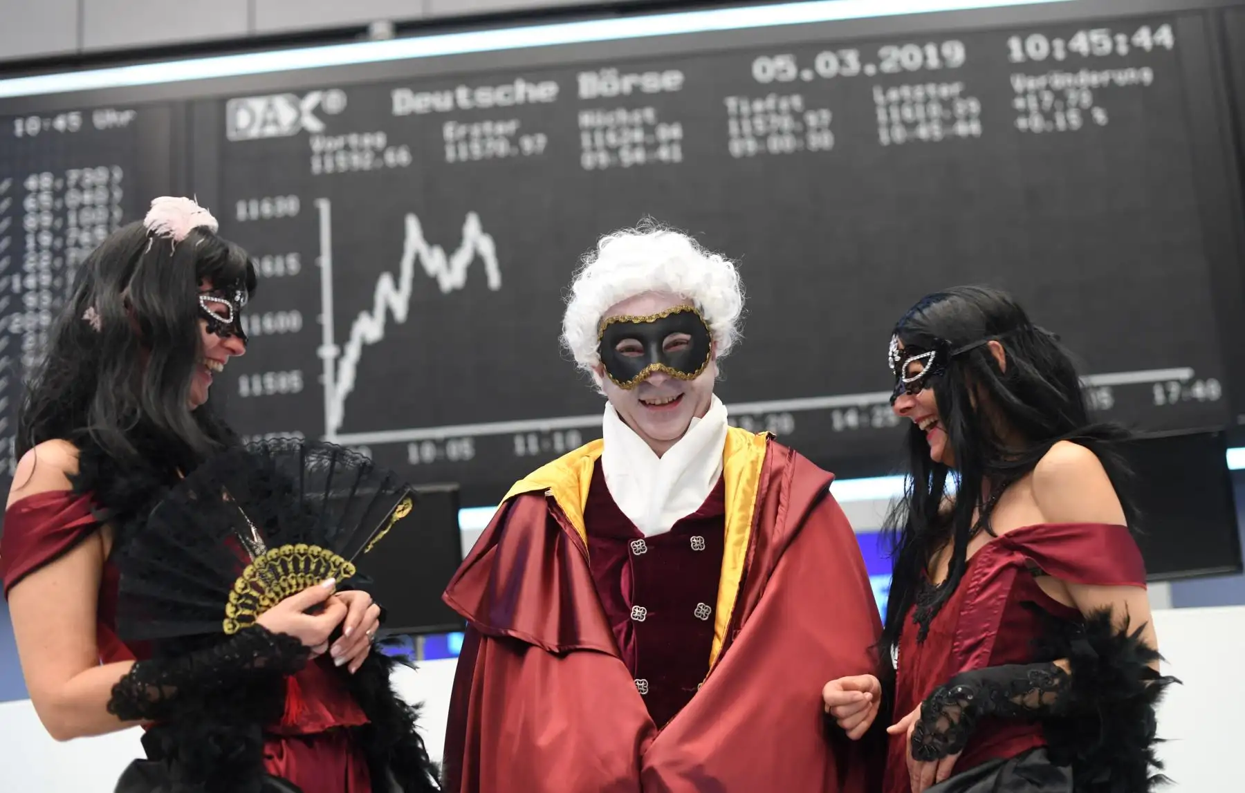 Comerciantes vestidos con trajes de carnaval posan frente a un tablero en la bolsa de valores de Fráncfort, Alemania. Foto: AFP