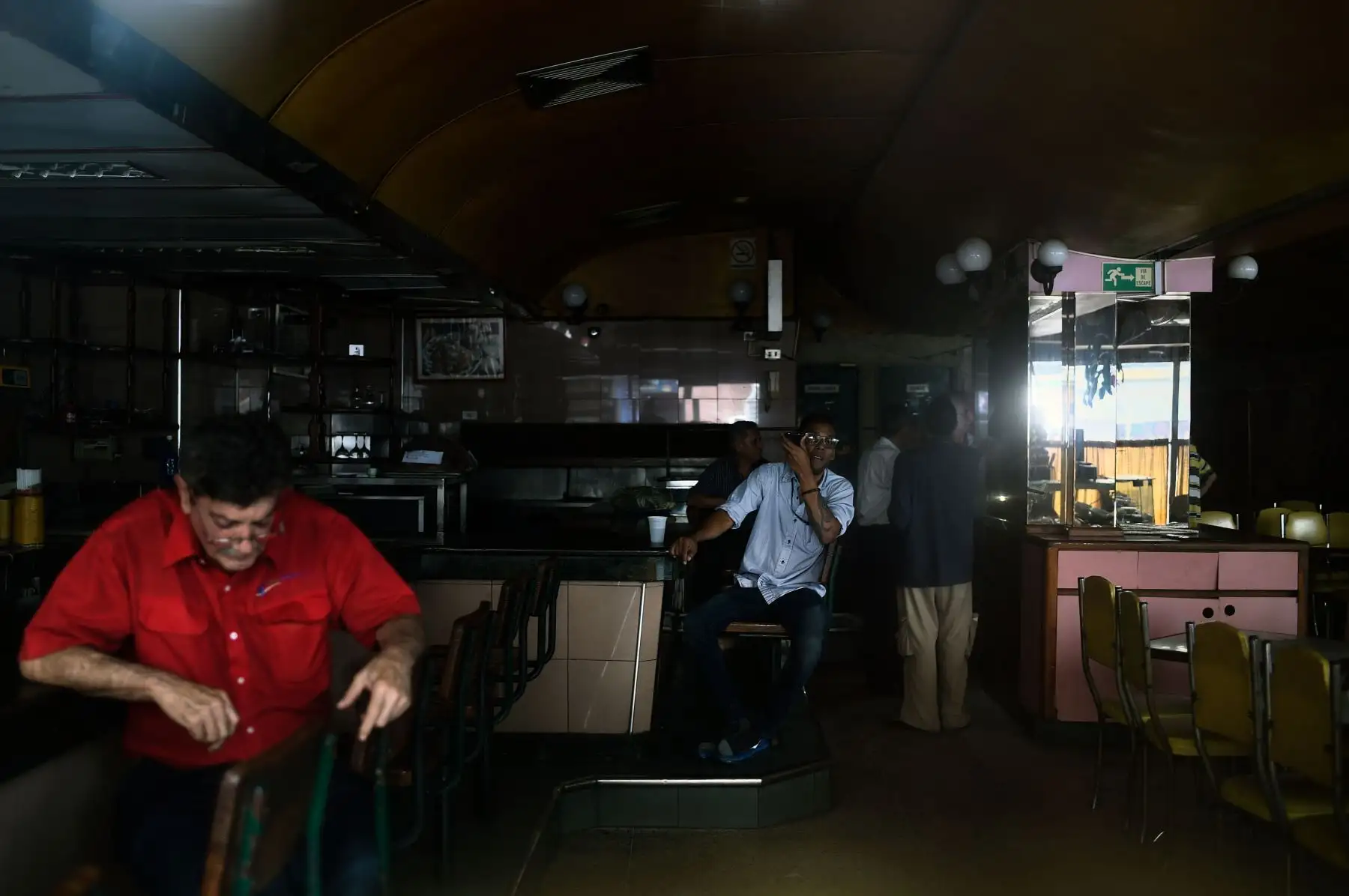 Los clientes permanecen en un restaurante durante un corte de energía en Caracas. El gobierno de Nicolás Maduro denunció un "sabotaje" contra la principal represa de energía eléctrica en el país, luego de un apagón masivo que dejó a Caracas y vastas regiones de Venezuela en el país. oscuridad. Foto:AFP