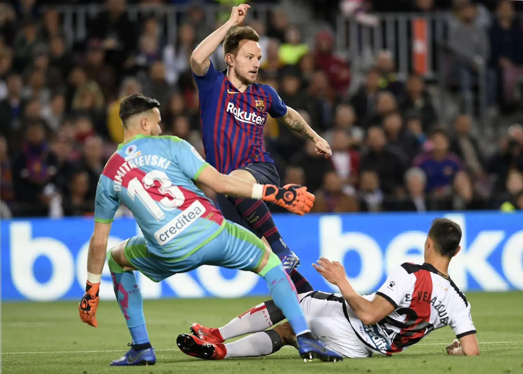 El centrocampista croata Ivan Rakitic (C) compite por el balón con el arquero del Rayo Vallecano, Stole Dimitrievski, y el defensa uruguayo Emiliano Velázquez, del Rayo Vallecano, durante el partido de fútbol de la liga española entre el FC Barcelona y el Rayo Vallecano.