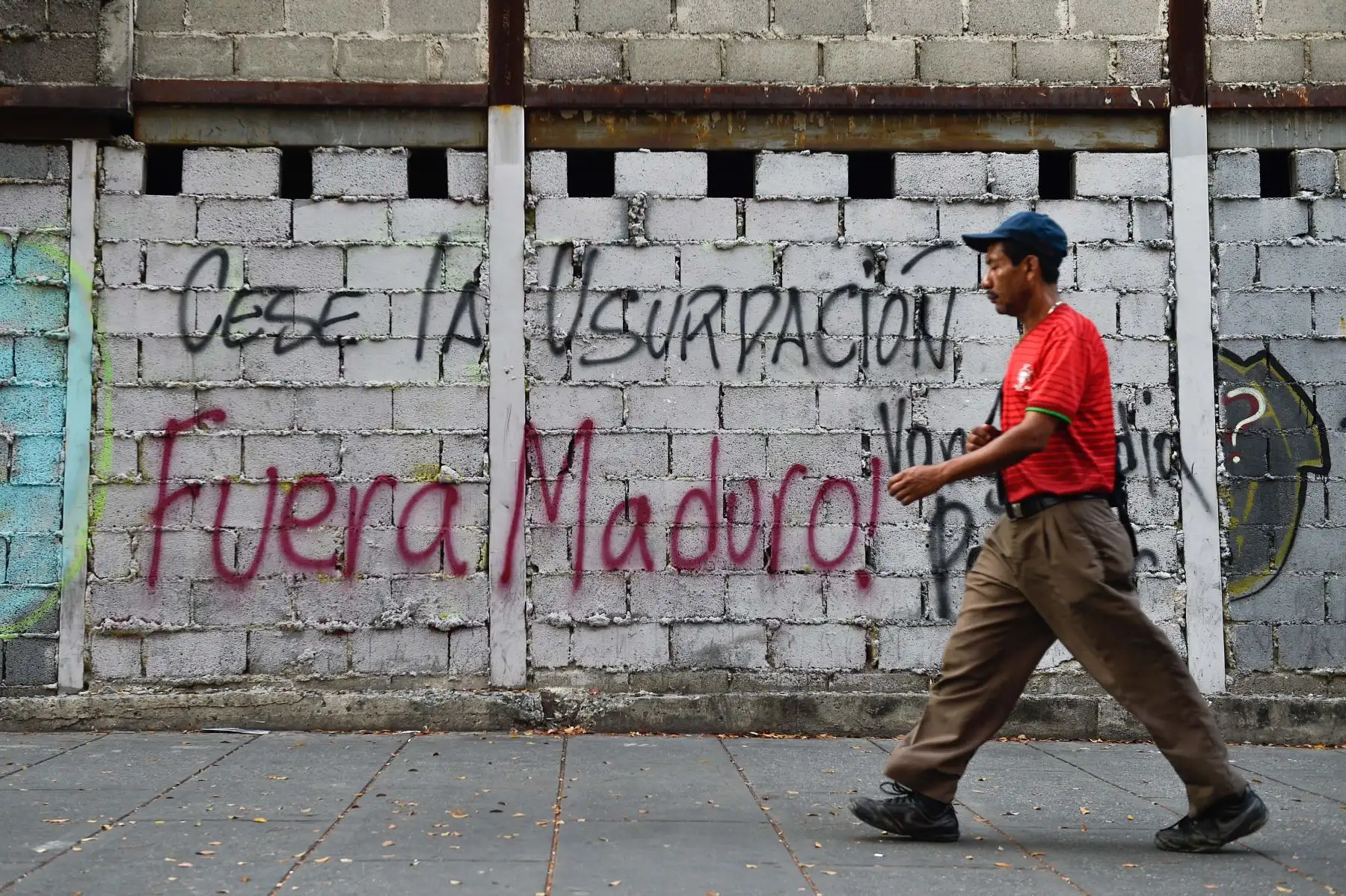 Un hombre pasa junto a un graffiti que dice "Fin de la usurpación. Maduro fuera", refiriéndose al presidente venezolano Nicolas Maduro en Caracas .Foto: AFP