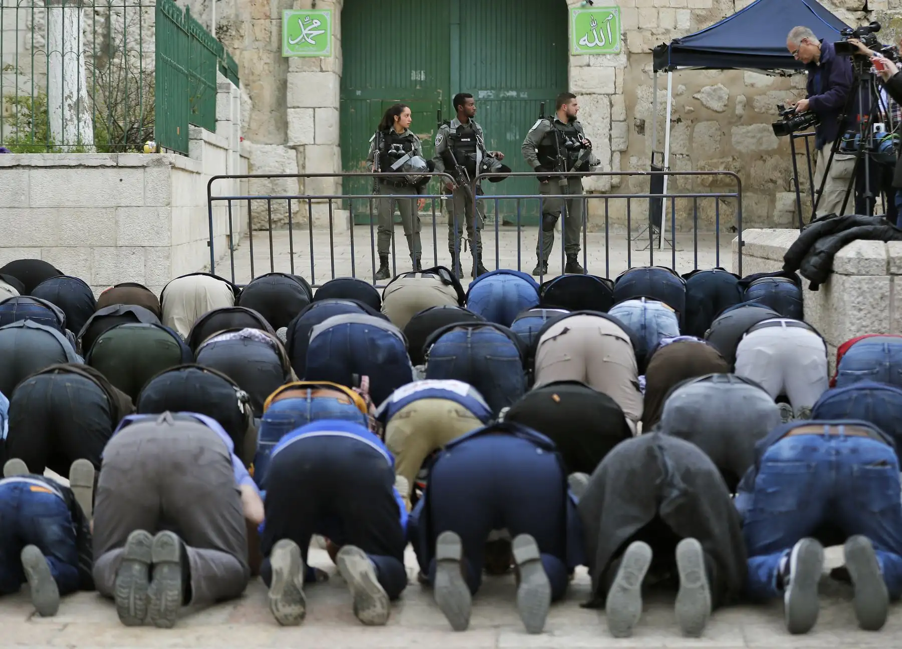 Fieles musulmanes palestinos rezan frente a una barrera de policías en la ciudad de Jerusalén. Foto: AFP
