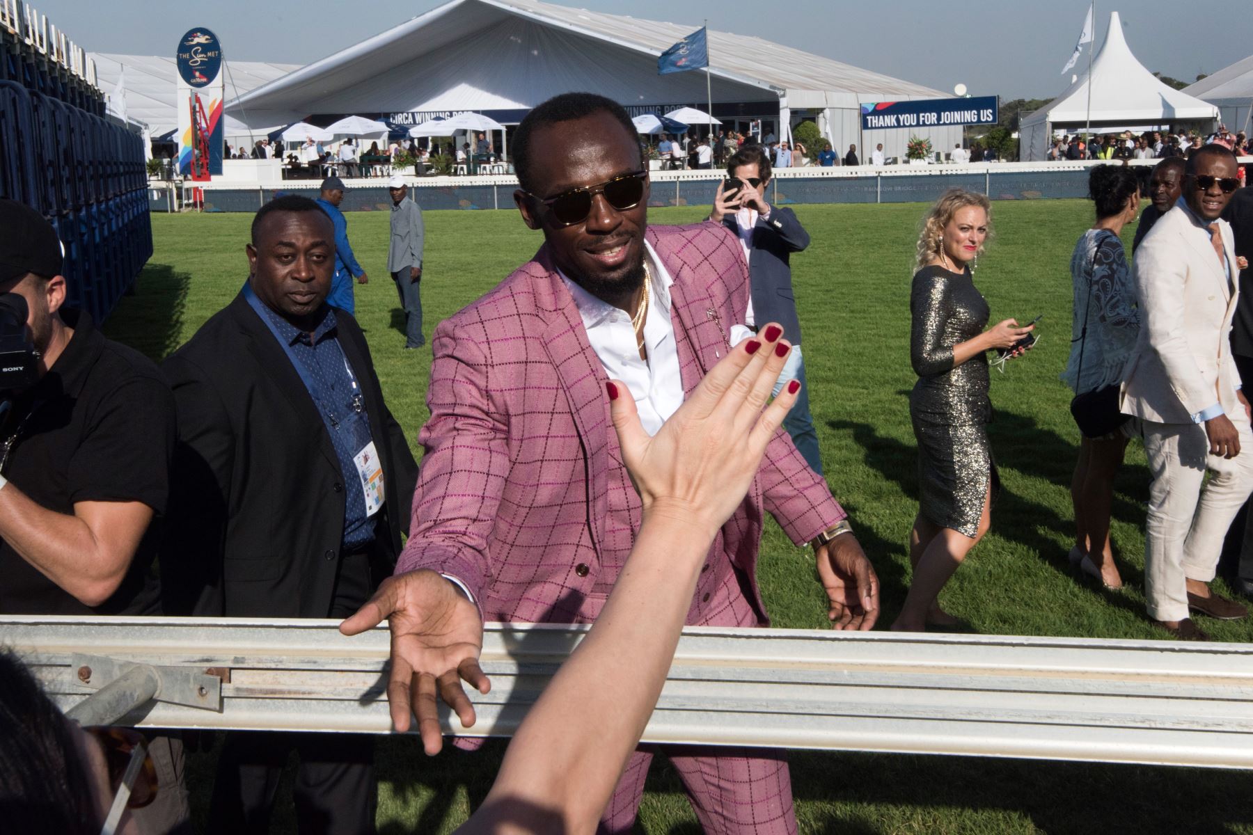 Usain Bolt, excampeón del mundo jamaicano y olímpico de velocidad, y ahora embajador de la marca Mumm Champagne, saluda a las personas cuando llega antes del inicio de la carrera de caballos Met en Ciudad del Cabo. Foto: AFP.