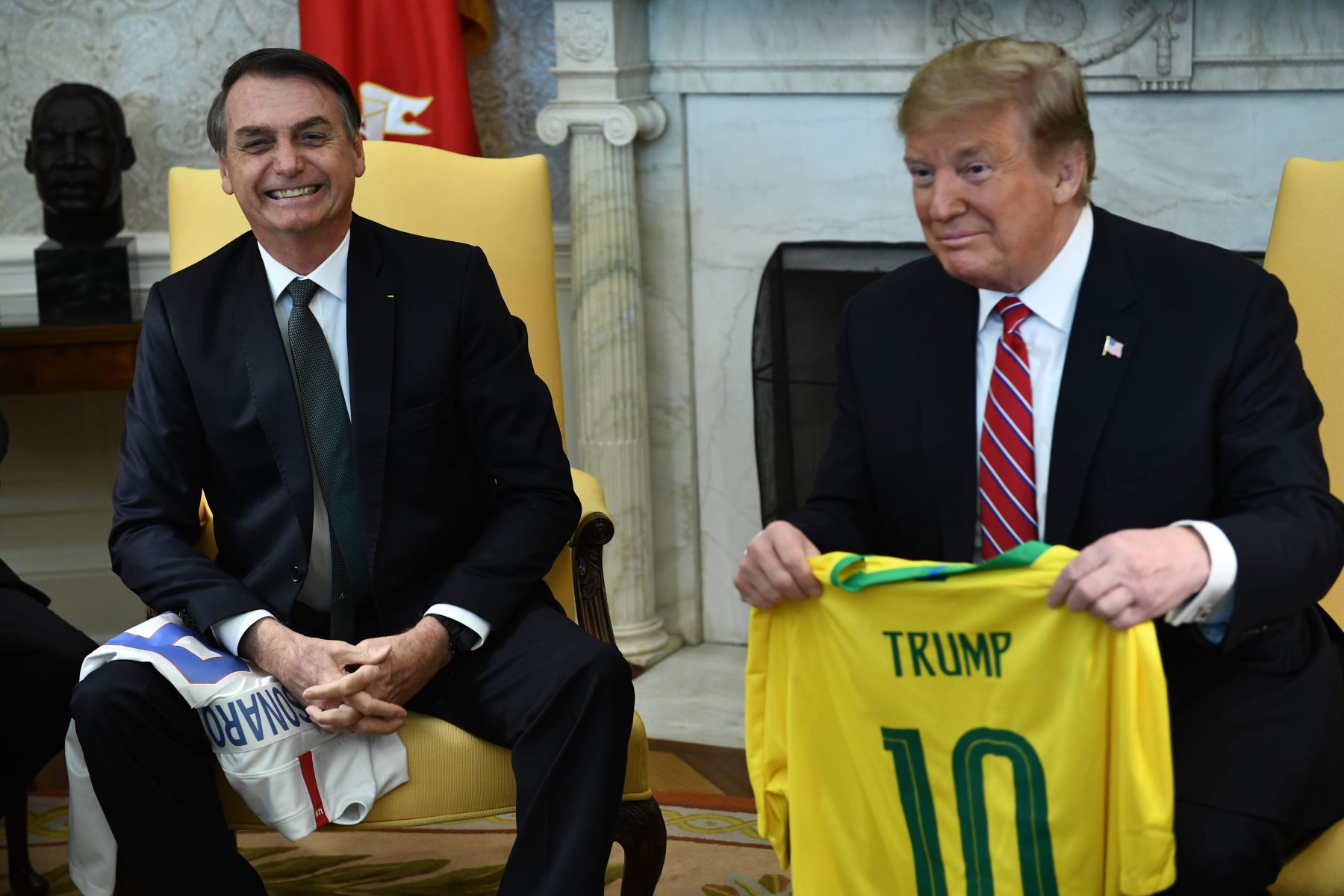 Donald Trump recibe una camiseta del equipo brasileño al reunirse con el presidente brasileño Jair Bolsonaro en la Oficina Oval de la Casa Blanca. Foto: AFP