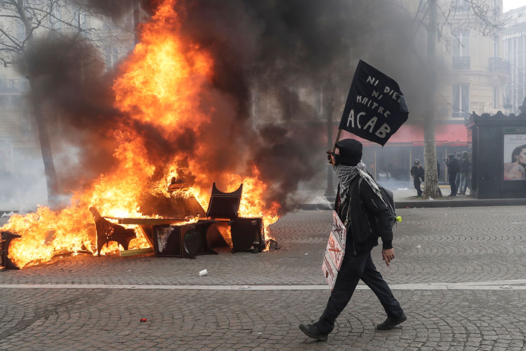 Foto de archivo del 16 de marzo de 2019, muestra a un manifestante pasa junto a una barricada en llamas durante los enfrentamientos con la policía antidisturbios en los Campos Elíseos de París. Foto: AFP