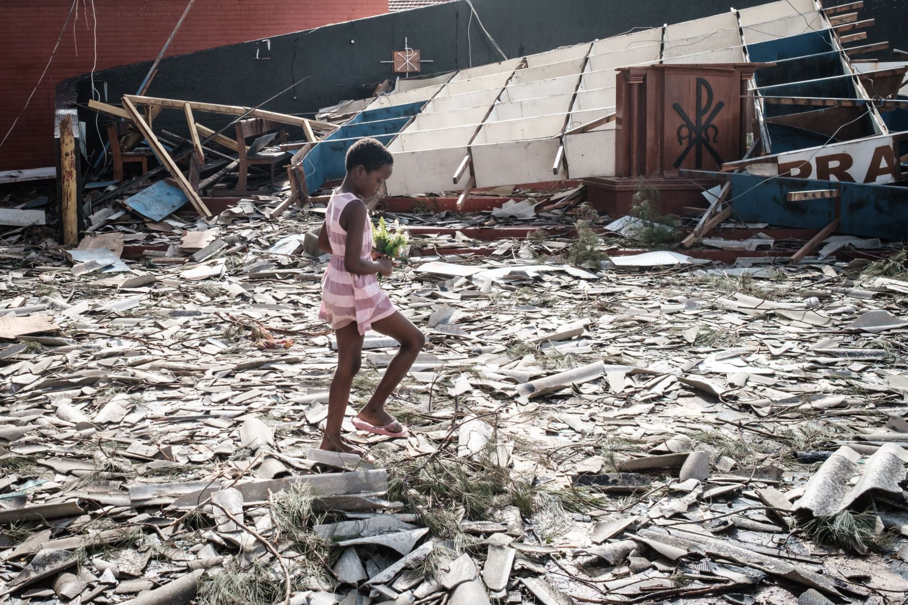 Una niña recoge flores artificiales de los escombros de un edificio destruido por el ciclón Idai en la Iglesia Católica del Sagrado Corazón en Beira, Mozambique, Foto : AFP