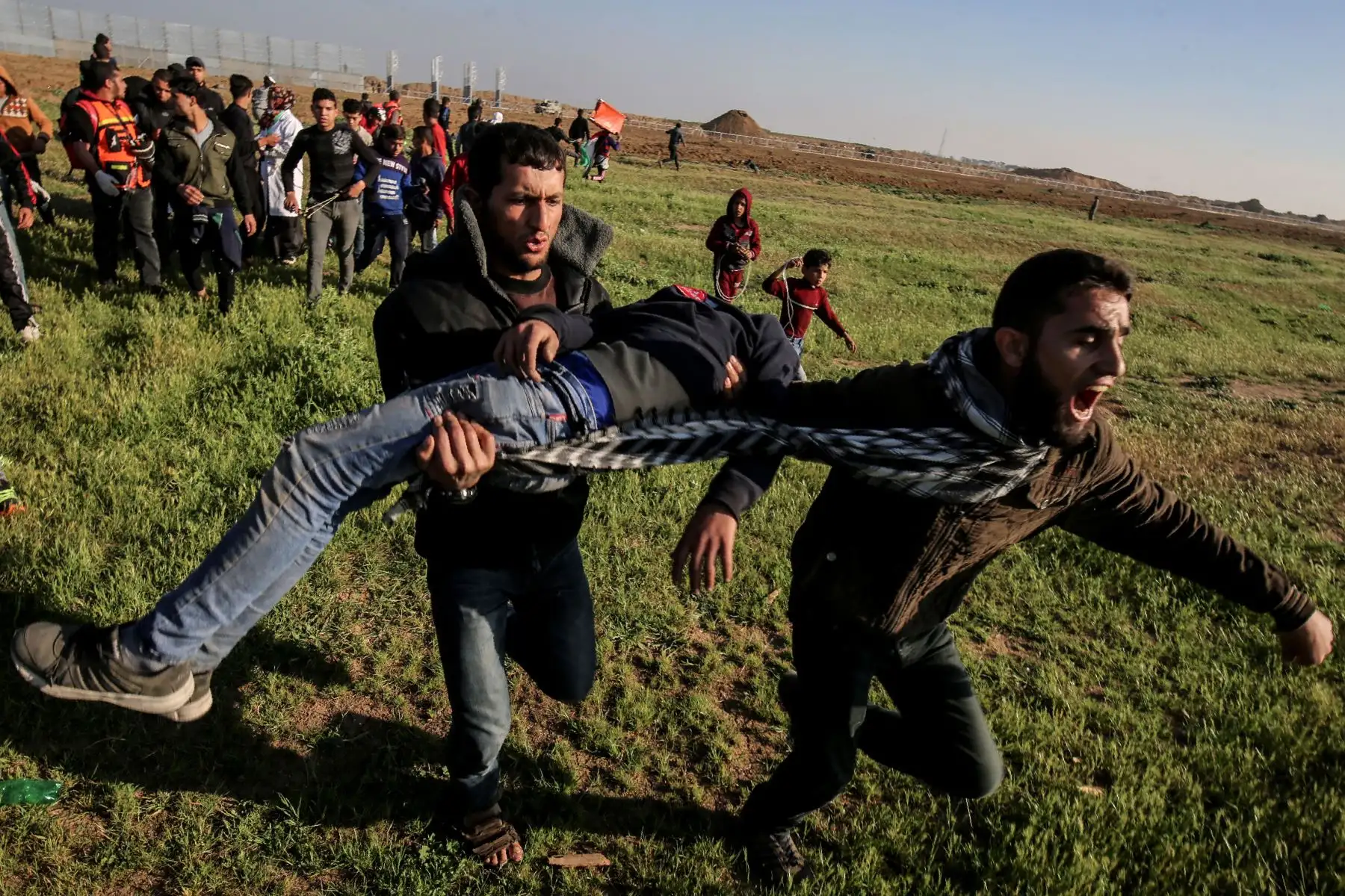 Palestinos cargan a un manifestante herido en la ciudad de Gaza. Foto: AFP