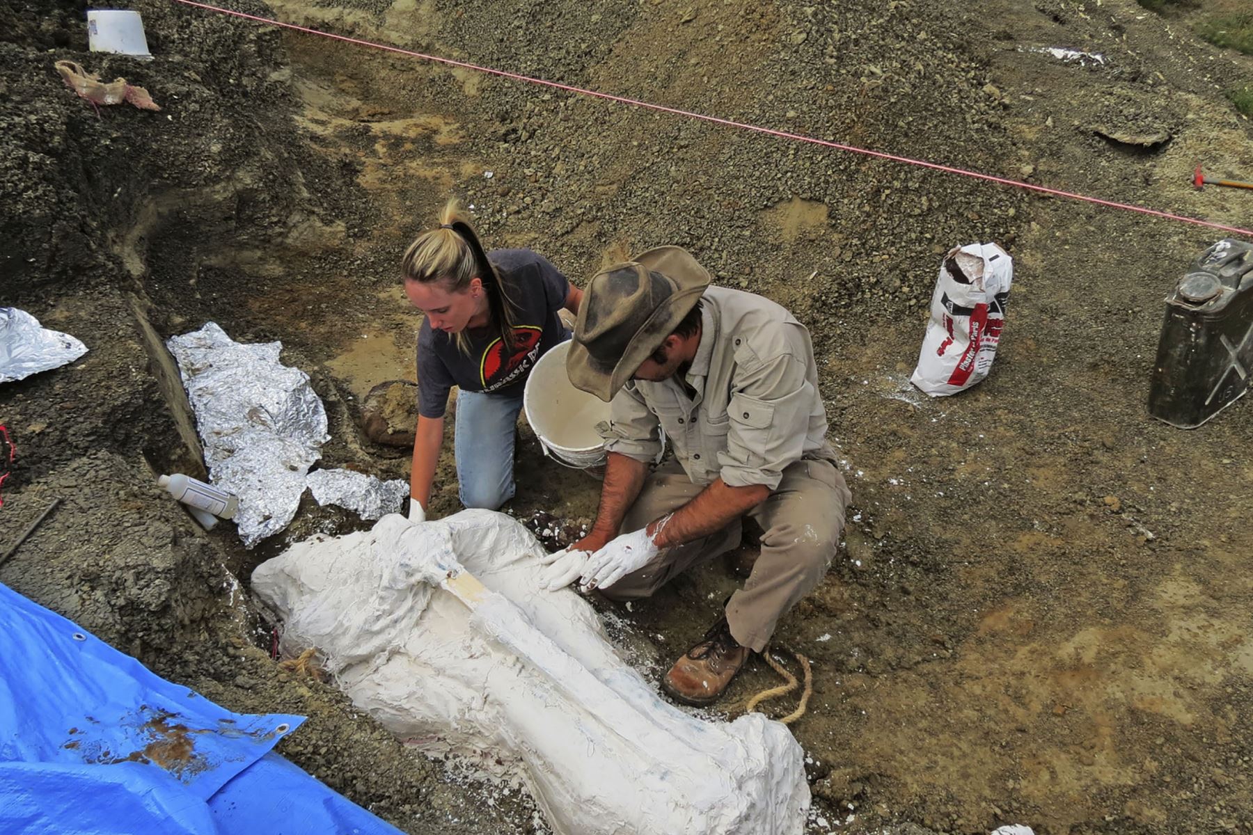 Foto de la Universidad de Kansas, muestra a Robert DePalma y al asistente de campo Kylie Ruble mientras excavan una losa de fósiles del depósito Tanis. Foto: AFP