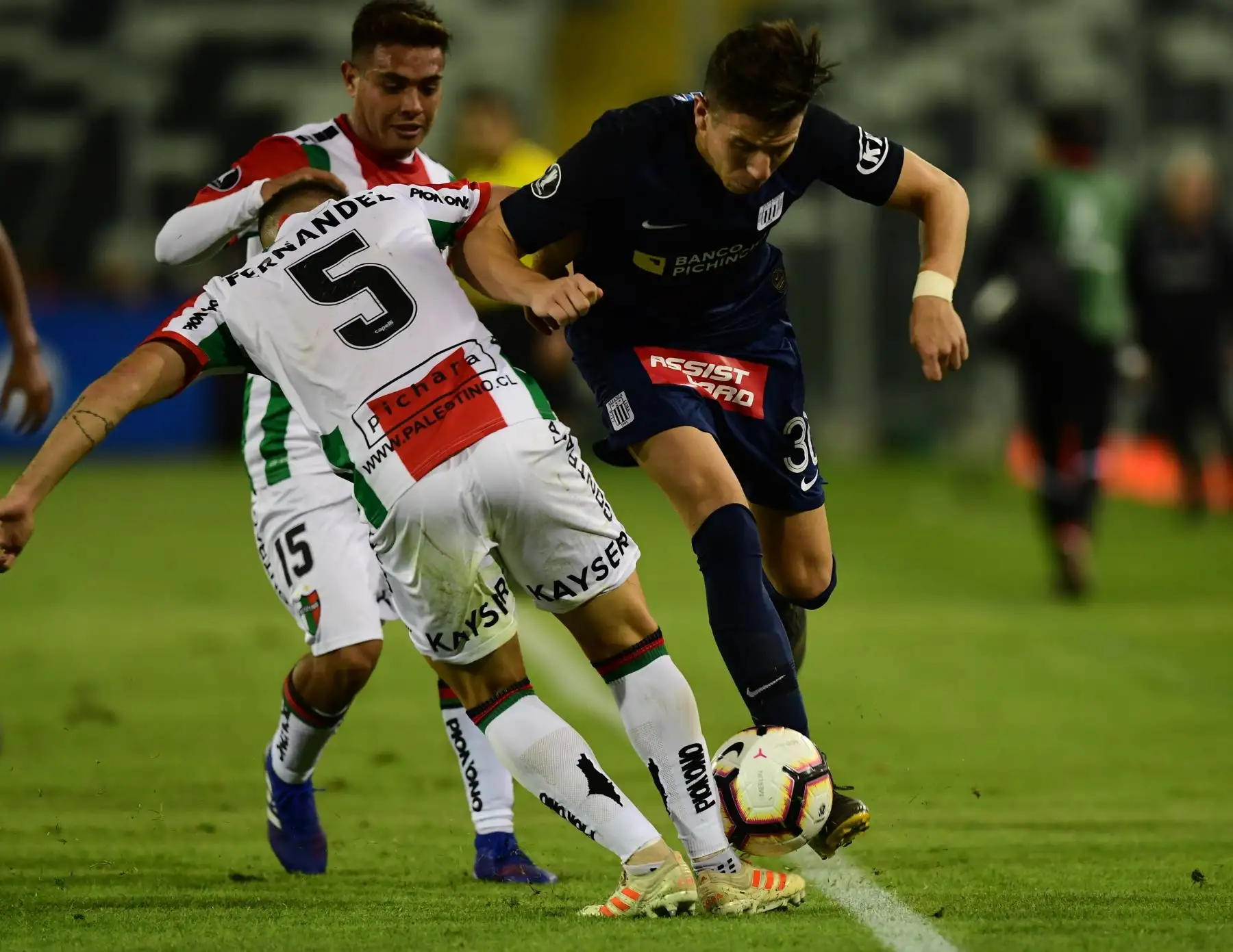 El palestino chileno Fabian Ahumada (L) y Julian Fernández (atrás) compiten por el balón contra la Alianza Lima Fabian Ugarriza (R) de Perú durante su partido de fútbol de la Copa Libertadores 2019 en el estadio Monumental de Santiago de Chile. Foto:AFP