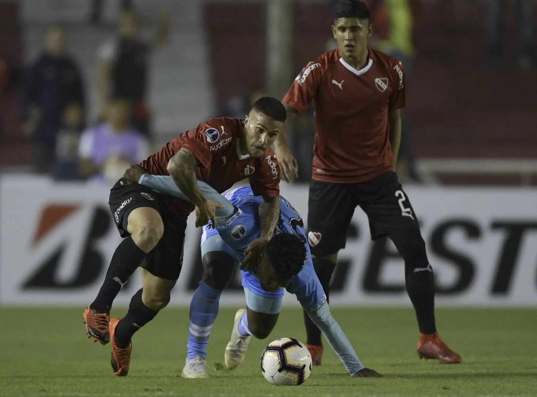 El delantero del Deportivo Binacional de Perú Marcos Rodríguez (C) compite por el balón con el defensa del Independiente Argentino Fabricio Bustos (L) durante su partido de fútbol de Copa Sudamericana en el estadio Libertadores de América en Avellaneda, Buenos Aires.Foto : AFP