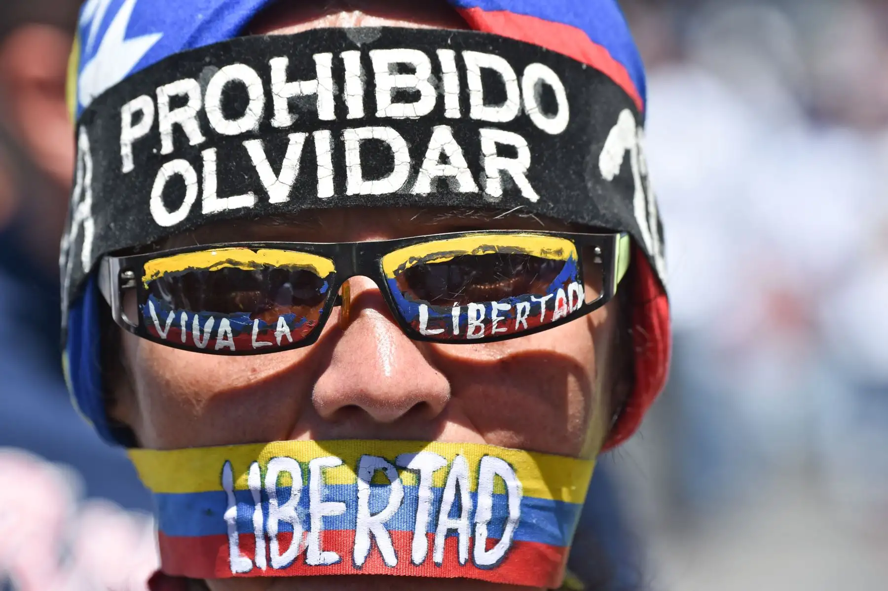 Un opositor al gobierno del presidente venezolano Nicolás Maduro con una diadema que dice "Prohibido olvidar", gafas que leen "Long Live Freedom" y una broma que lee "Libertad", participa en una demostración en Venezuela. Foto:AFP