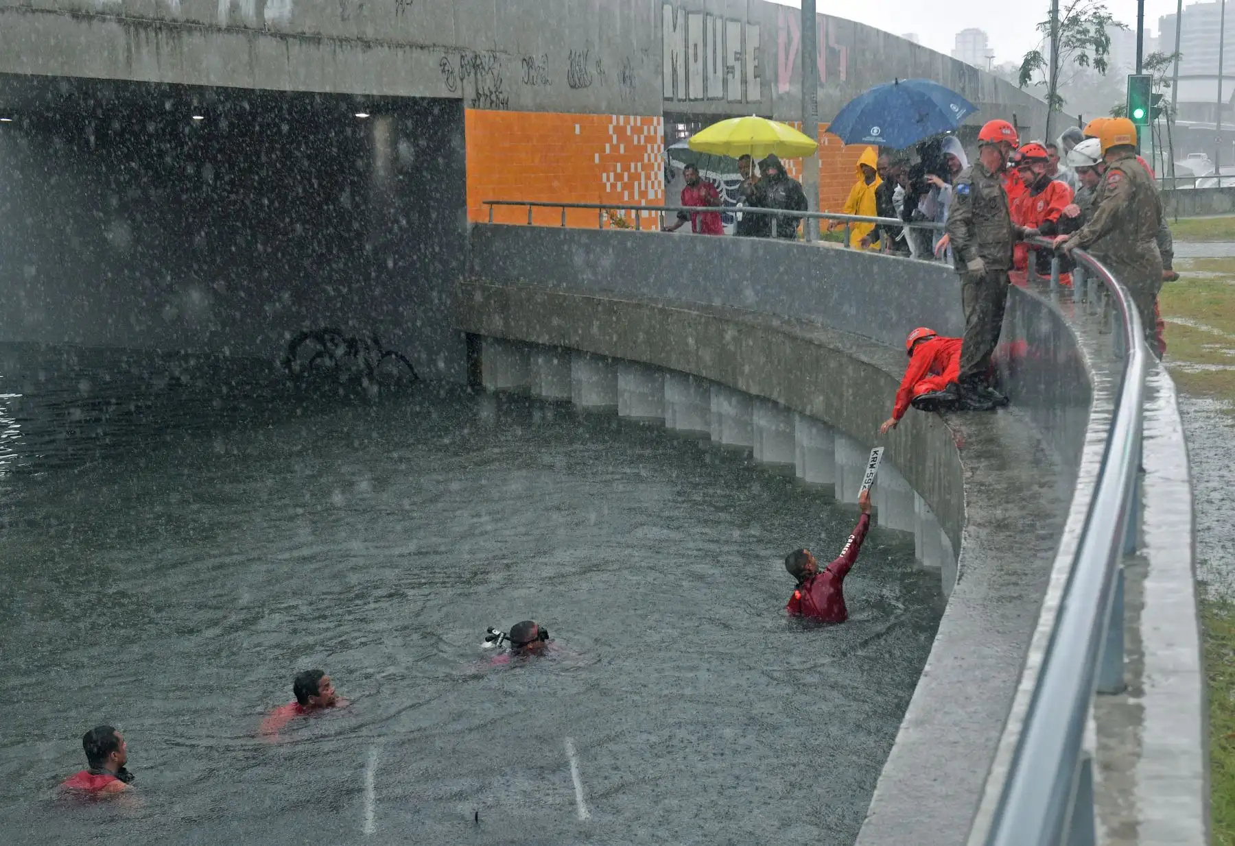 Un bombero de la unidad submarina recupera una placa de matrícula de un automóvil sumergido en un túnel de carretera durante las fuertes lluvias en Río de Janeiro, Brasil. Foto: AFP