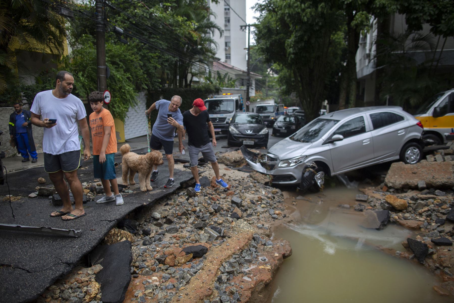 La gente mira los autos dañados después de las fuertes lluvias en el barrio Jardim Botánico en Río de Janeiro, Brasil. Foto: AFP