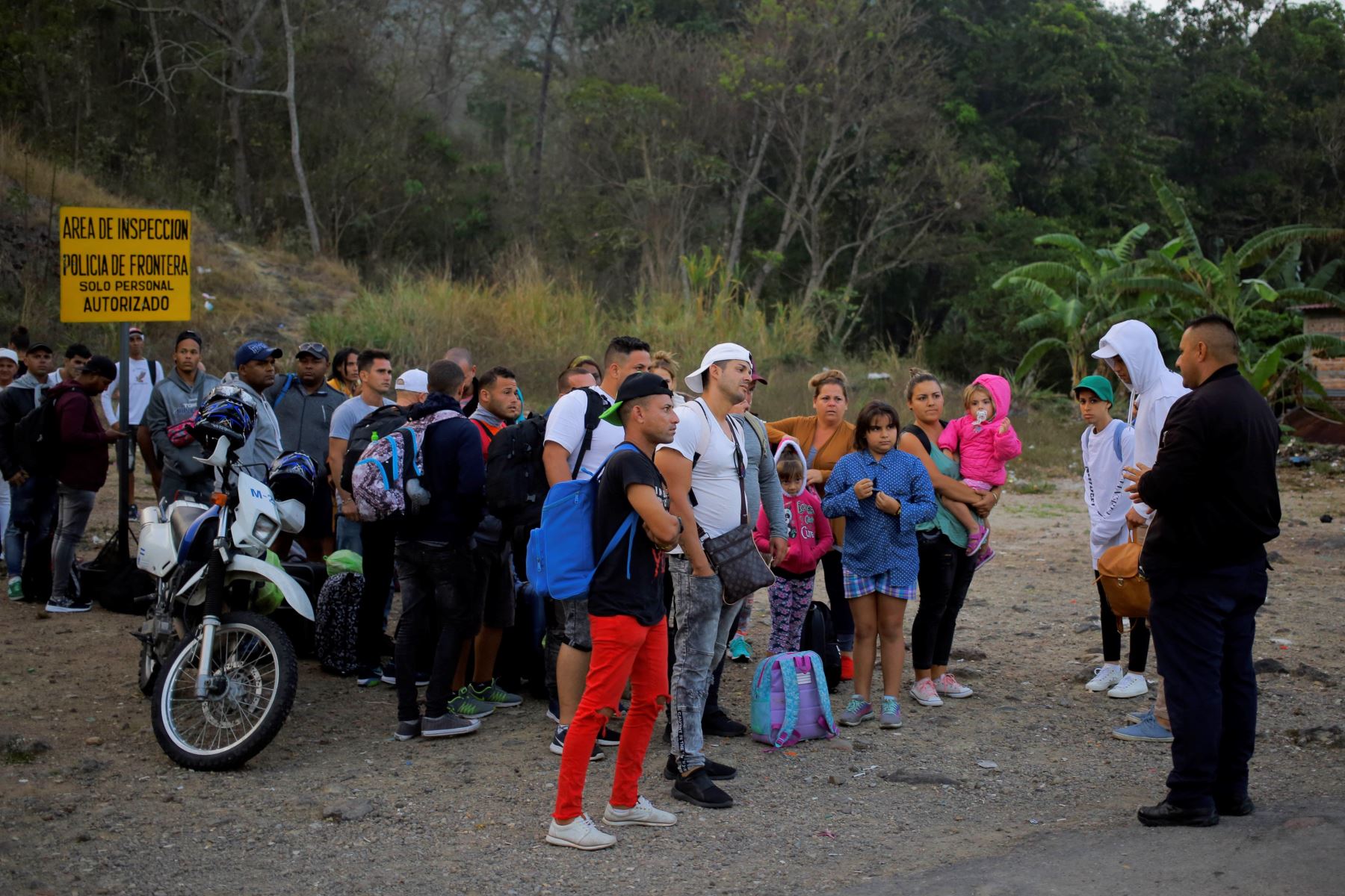 Migrantes cubanos hablan con un agente de migración este viernes al llegar a la Aduana de Agua Caliente (Honduras), fronterizo con Guatemala. Foto: EFE