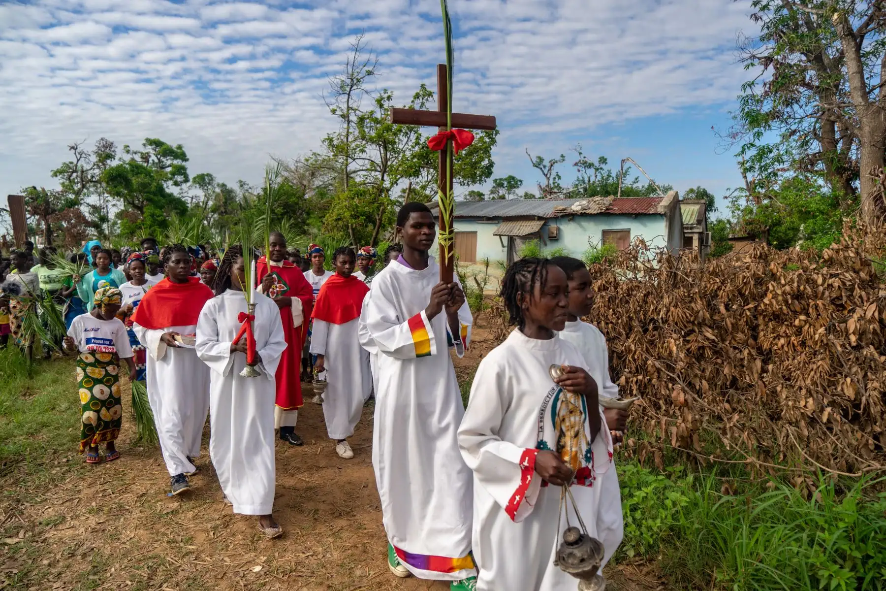 Un congregante sostiene una cruz santa que pasa junto a los escombros durante una marcha para conmemorar el Domingo de Ramos en la Iglesia Católica Parroquial de la Dama de Gracia en Barrio Manasse, distrito de Buzi, provincia de Sofala, Mozambique. Foto : AFP