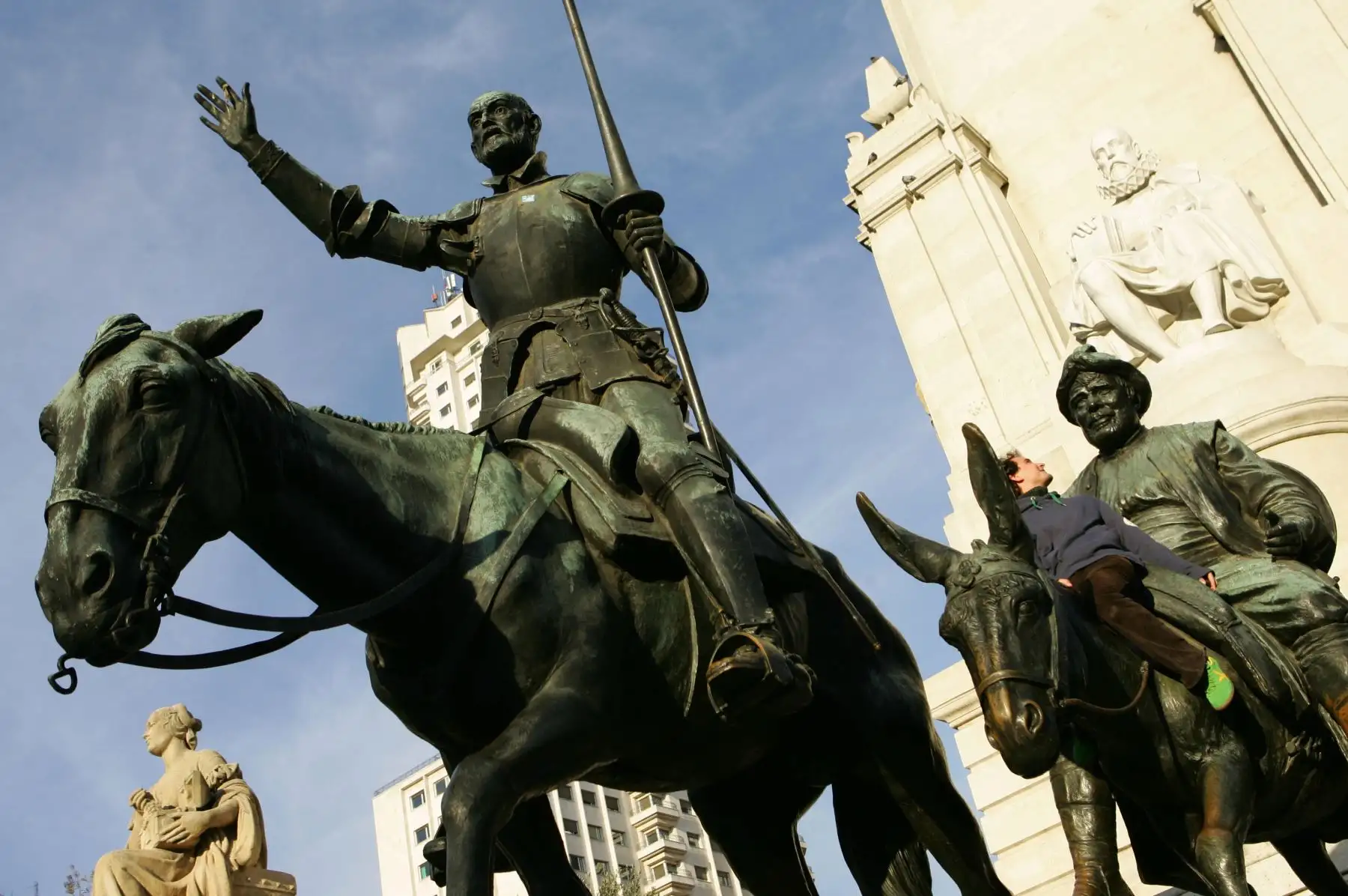 Un turista se sienta en la estatua de Sancho Panza (R), compañero de Don Quijote en la plaza de España de Madrid.
Foto: AFP