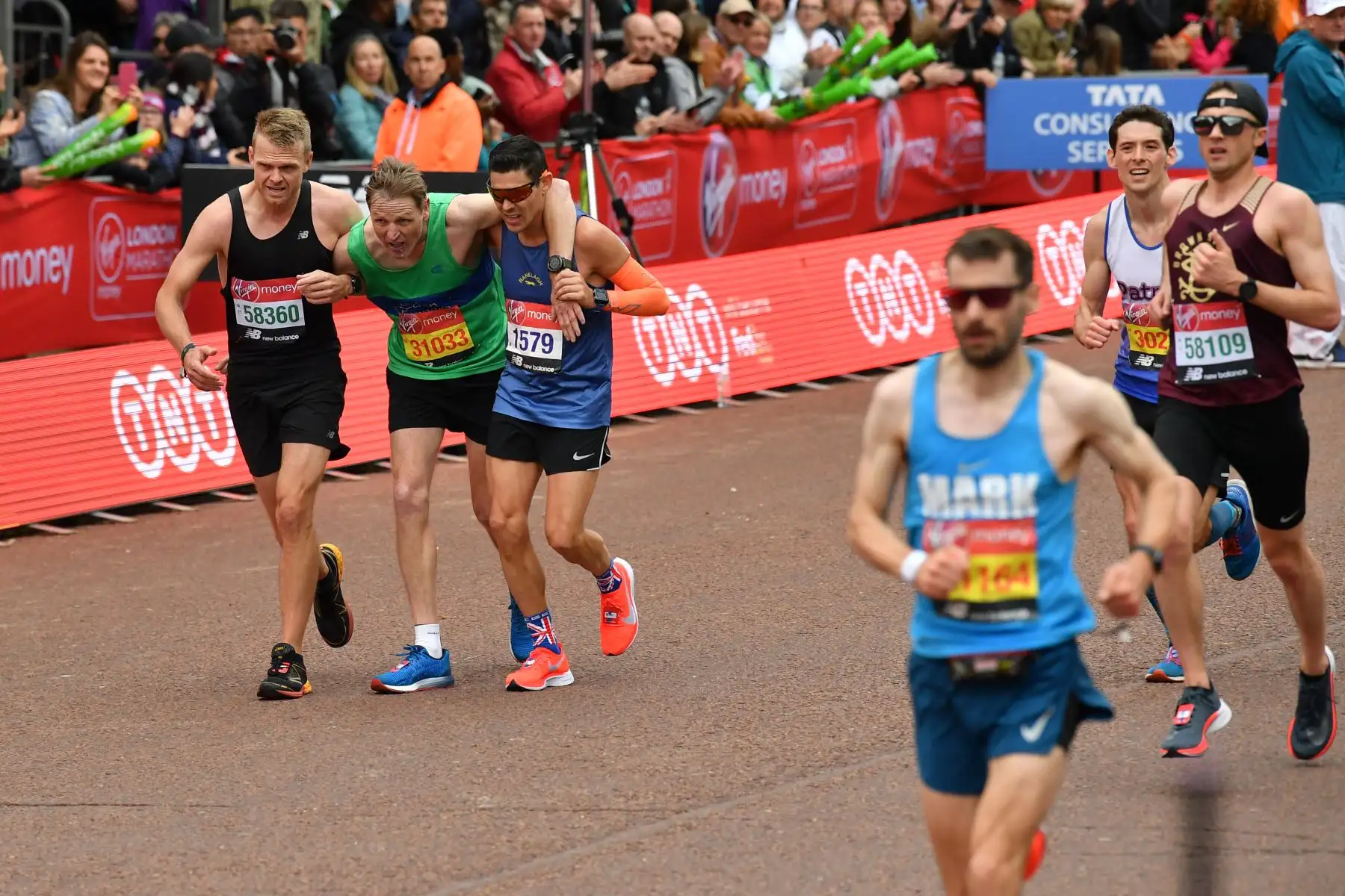 Maratonistas ayudan  a un corredor a la línea en el Maratón de Londres 2019.
Foto:AFP