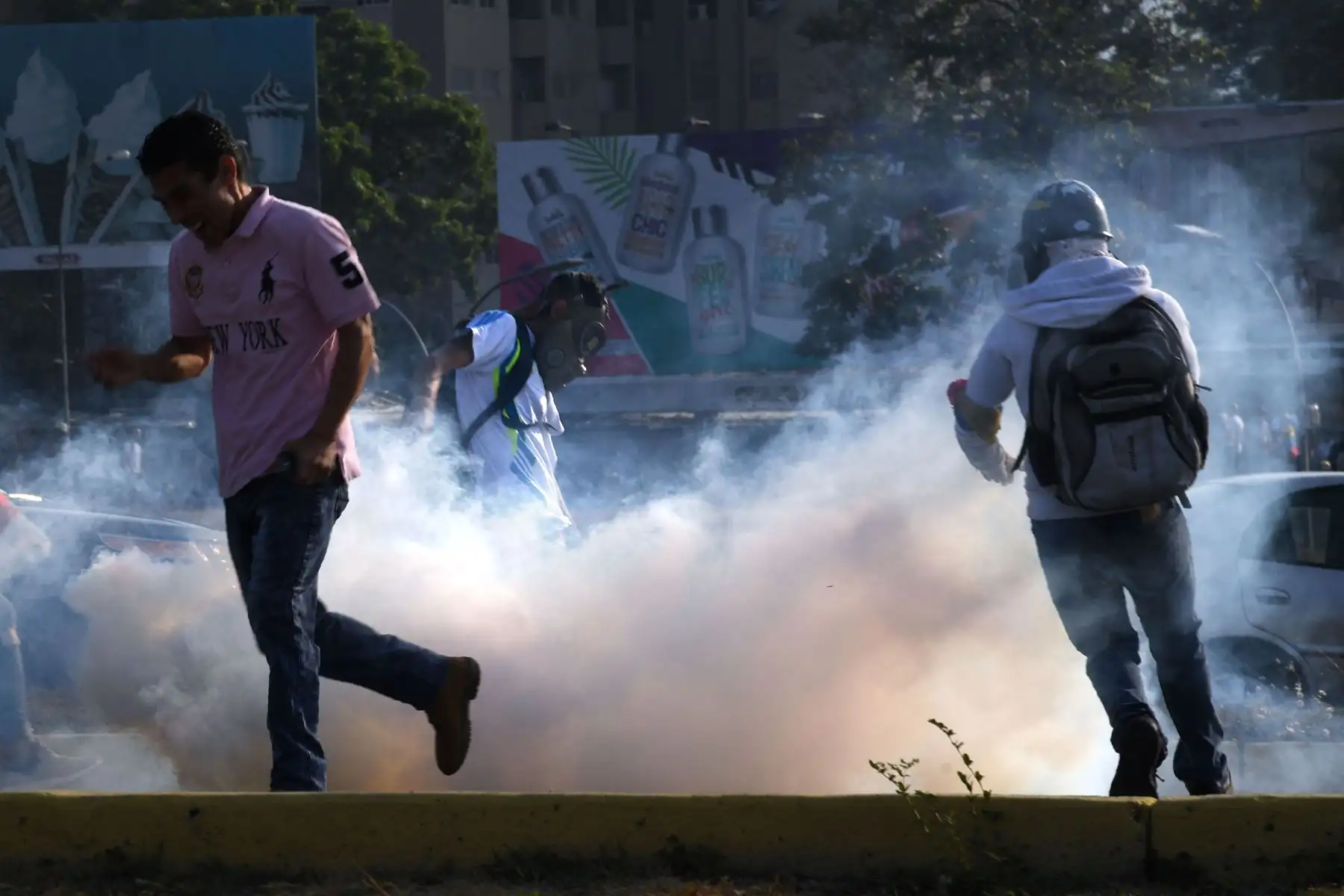 Simpatizantes del presidente interno Juan Guaidó se protegen de las bombas lacrimógenas que las fuerzas de seguridad leales al Gobierno de Nicolás Maduro lanzan en la base militar de La Carlota, donde se encuentra el presidente interino Juan Guaidó y un grupo de militares que le apoyan.Foto: AFP Simpatizantes del presidente interno Juan Guaidó se protegen de las bombas lacrimógenas que las fuerzas de seguridad leales al Gobierno de Nicolás Maduro lanzan en la base militar de La Carlota, donde se encuentra el presidente interino Juan Guaidó y un grupo de militares que le apoyan.Foto: AFP