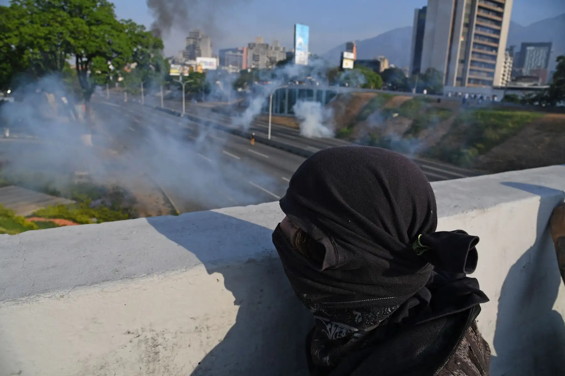 Simpatizantes del presidente interno Juan Guaidó se protegen de las bombas lacrimógenas que las fuerzas de seguridad leales al Gobierno de Nicolás Maduro lanzan en la base militar de La Carlota, donde se encuentra el presidente interino Juan Guaidó y un grupo de militares que le apoyan.Foto: AFP Simpatizantes del presidente interno Juan Guaidó se protegen de las bombas lacrimógenas que las fuerzas de seguridad leales al Gobierno de Nicolás Maduro lanzan en la base militar de La Carlota, donde se encuentra el presidente interino Juan Guaidó y un grupo de militares que le apoyan.Foto: AFP